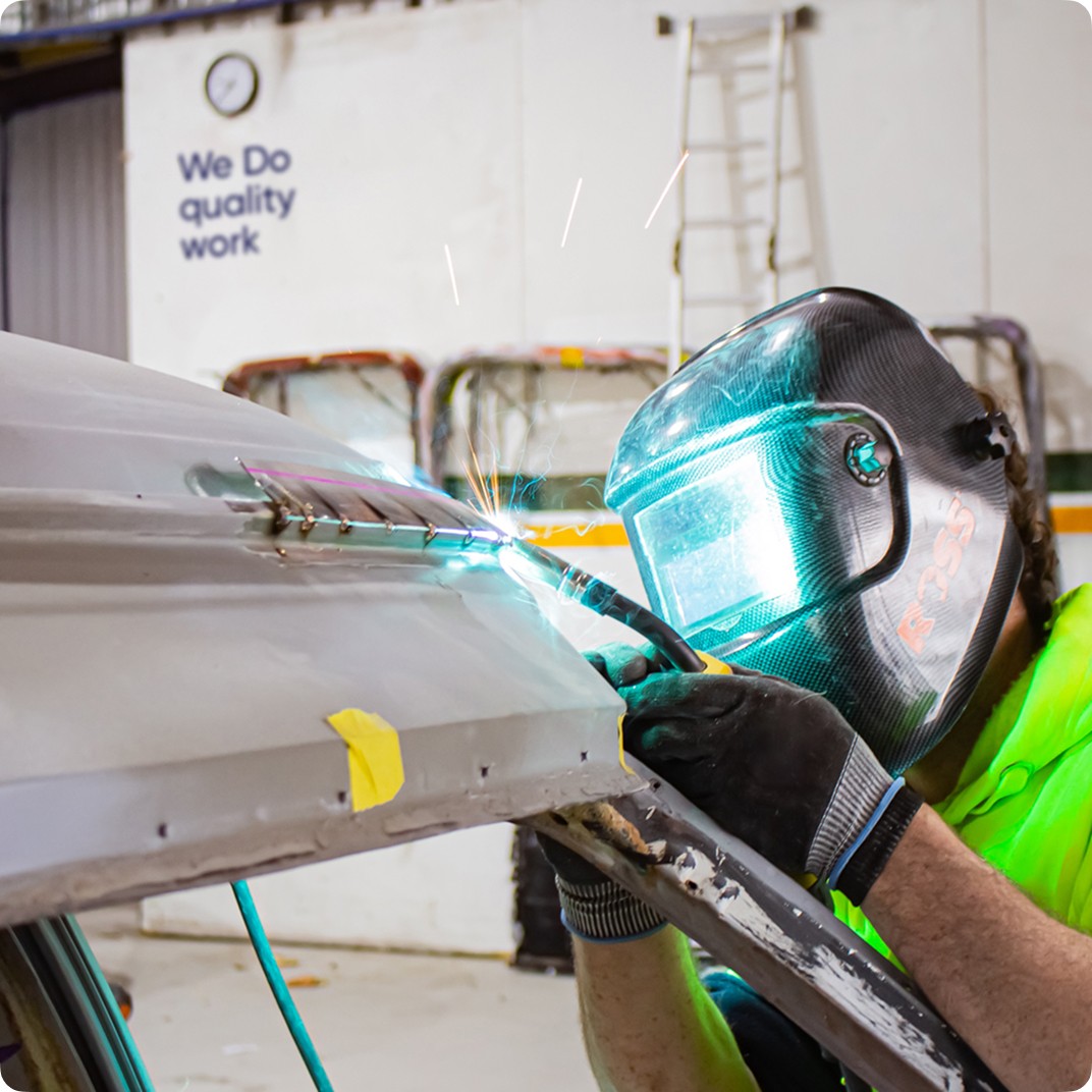 Welder in mask repairs metal with sparks