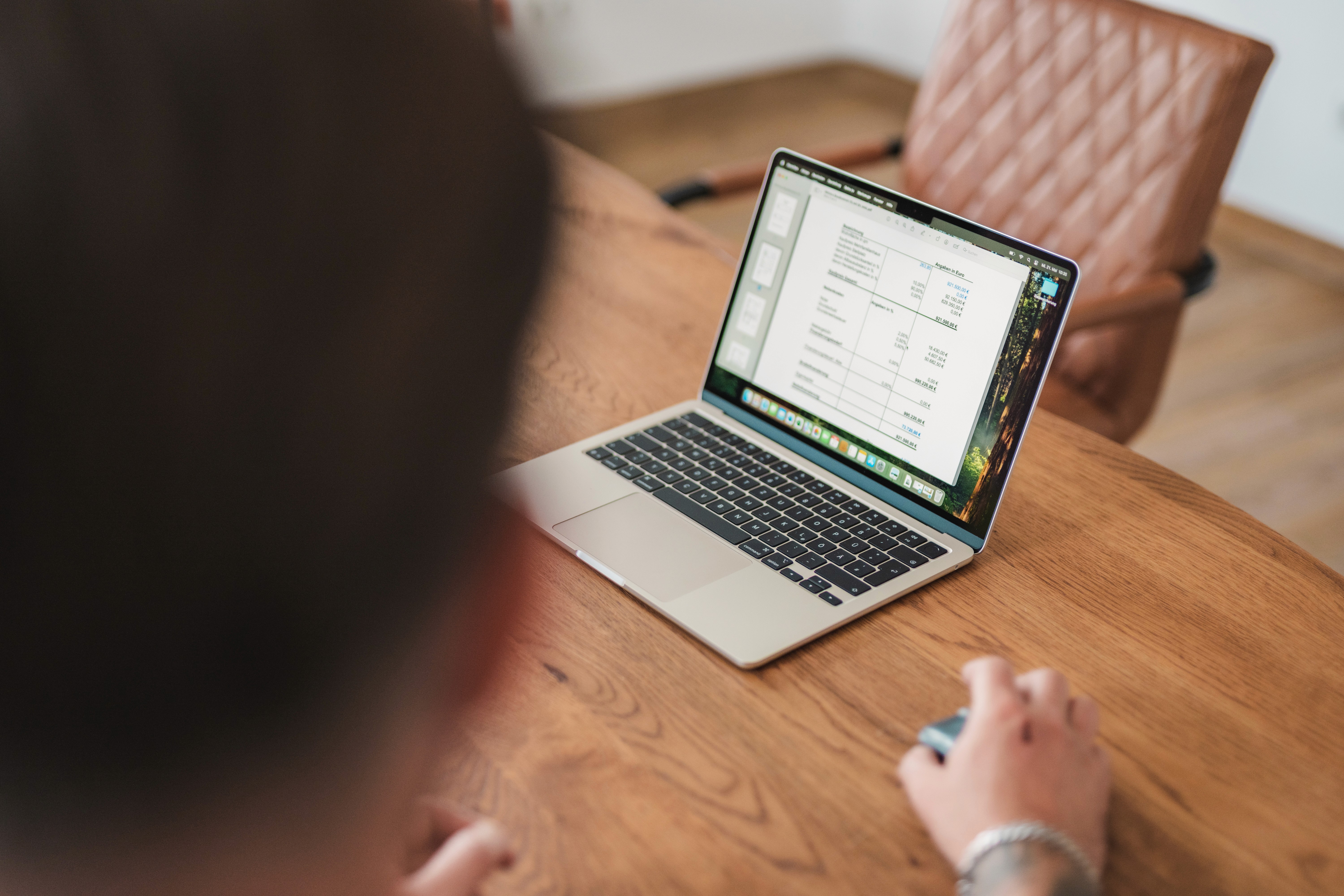 Ein Tisch und eine Hand an einer Computermaus zeigt eine Rechnung auf dem Computer