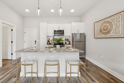 A bright kitchen with white cabinetry and a stylish bar stool positioned at the counter.