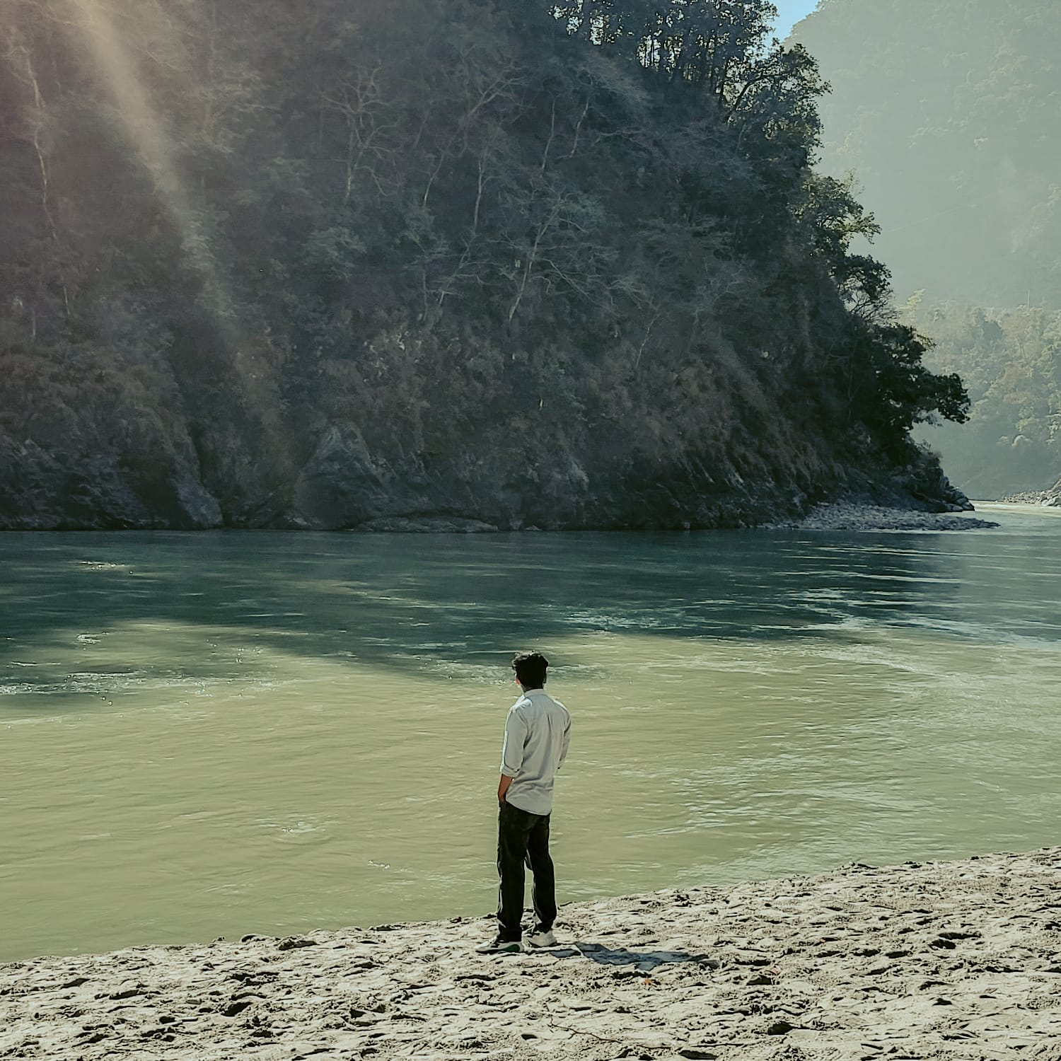 Adnan standing by a river, reflecting on the landscape