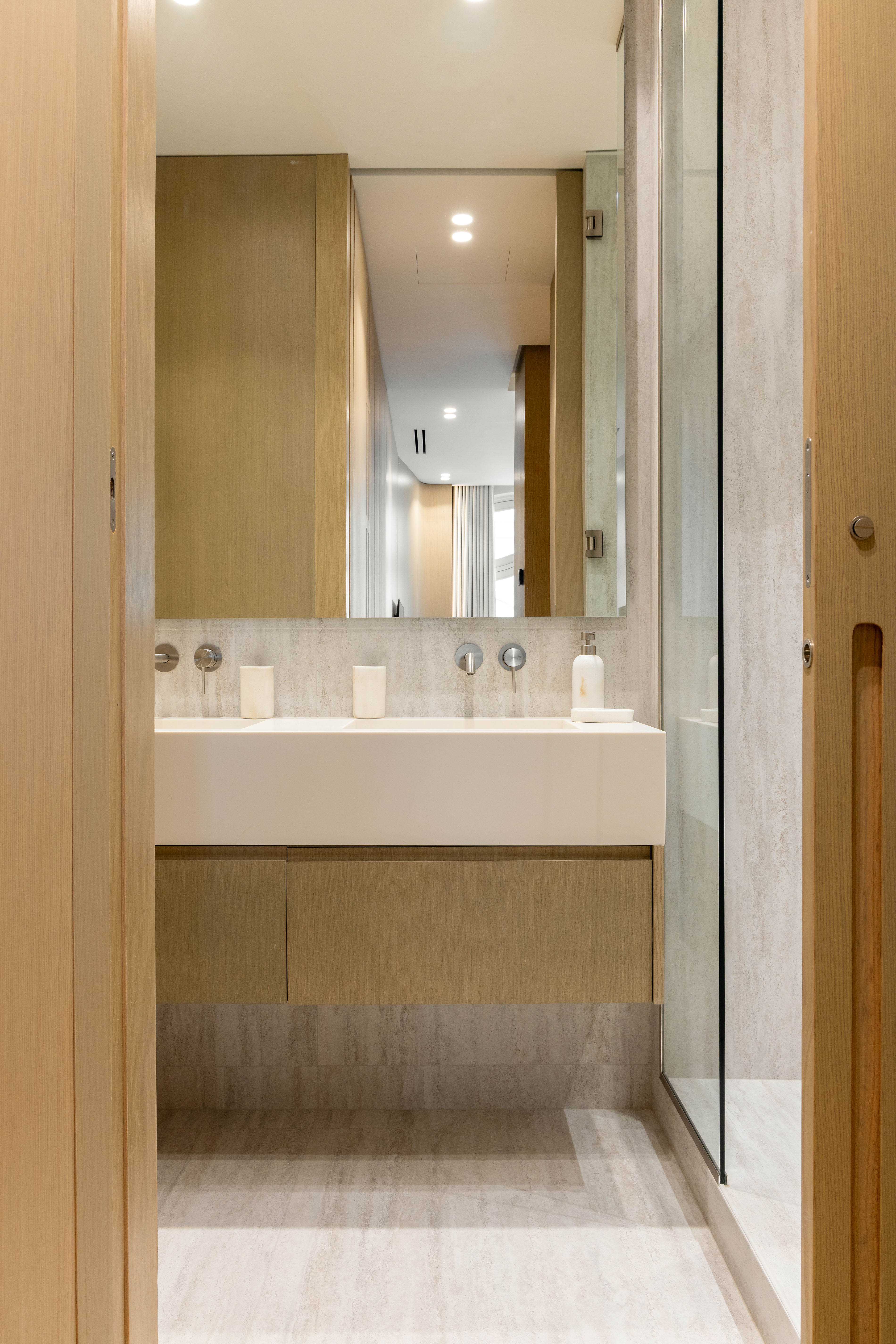 Salle de bain secondaire avec double vasque, grand miroir, revetement pierre et paroi de douche vitree