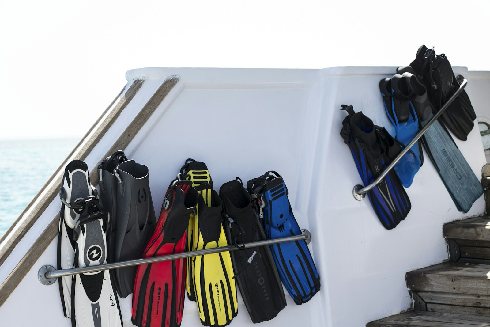 Colorful dive fins hanging to dry on a boat rail