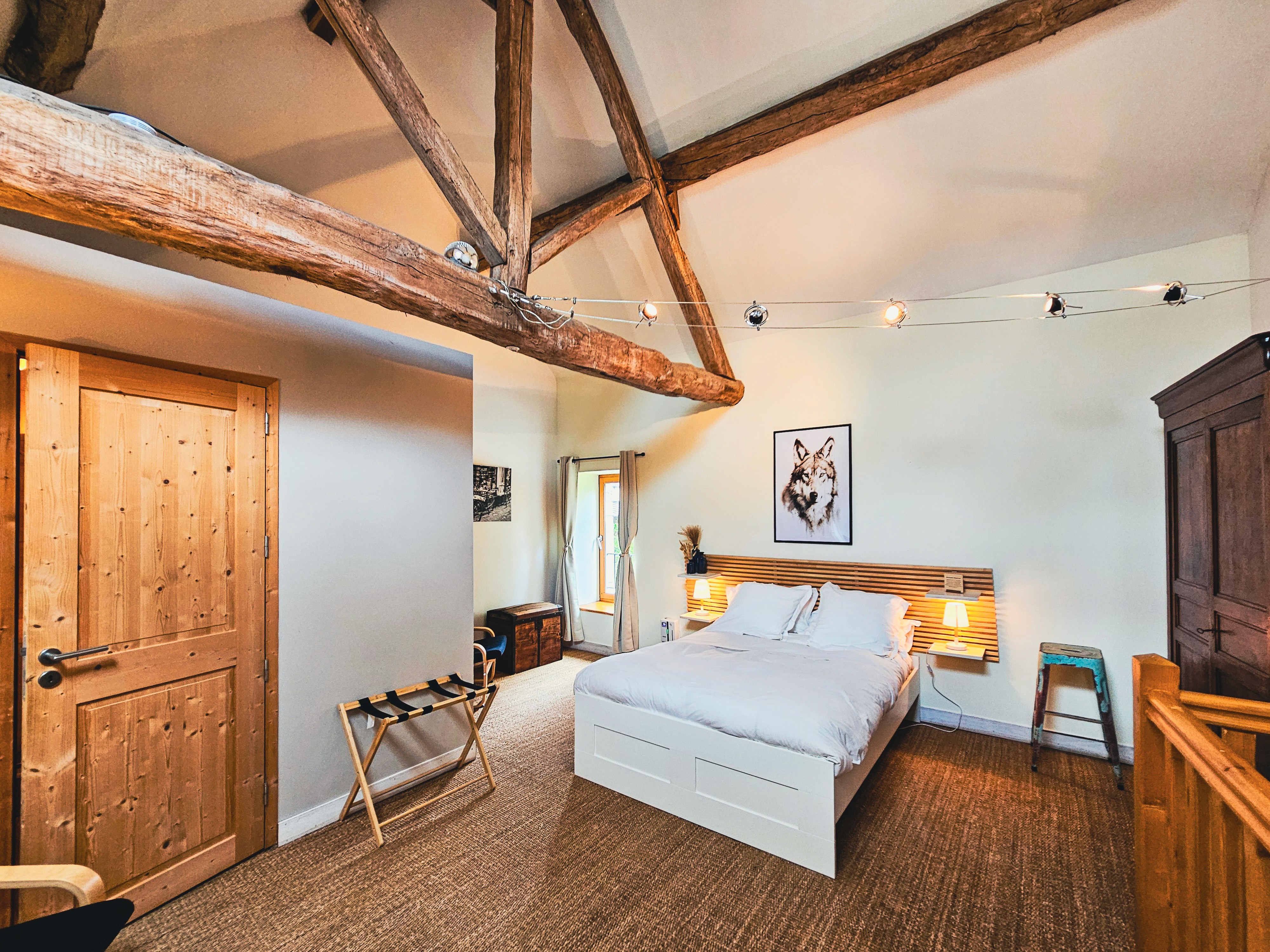 Chambre avec lit double, poutres apparentes et mobilier en bois.