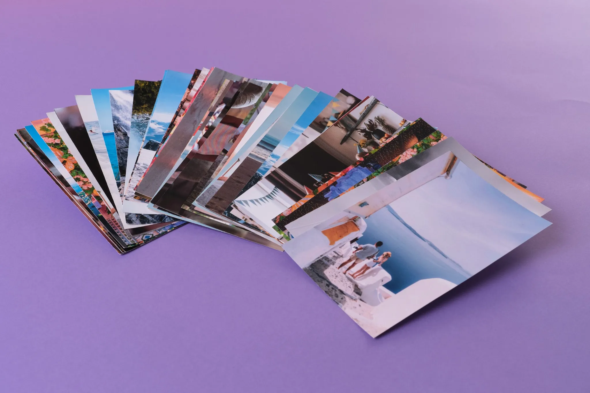 Montagem de fotos reveladas com cenas de família, praia, infância e viagens espalhadas sobre a mesa