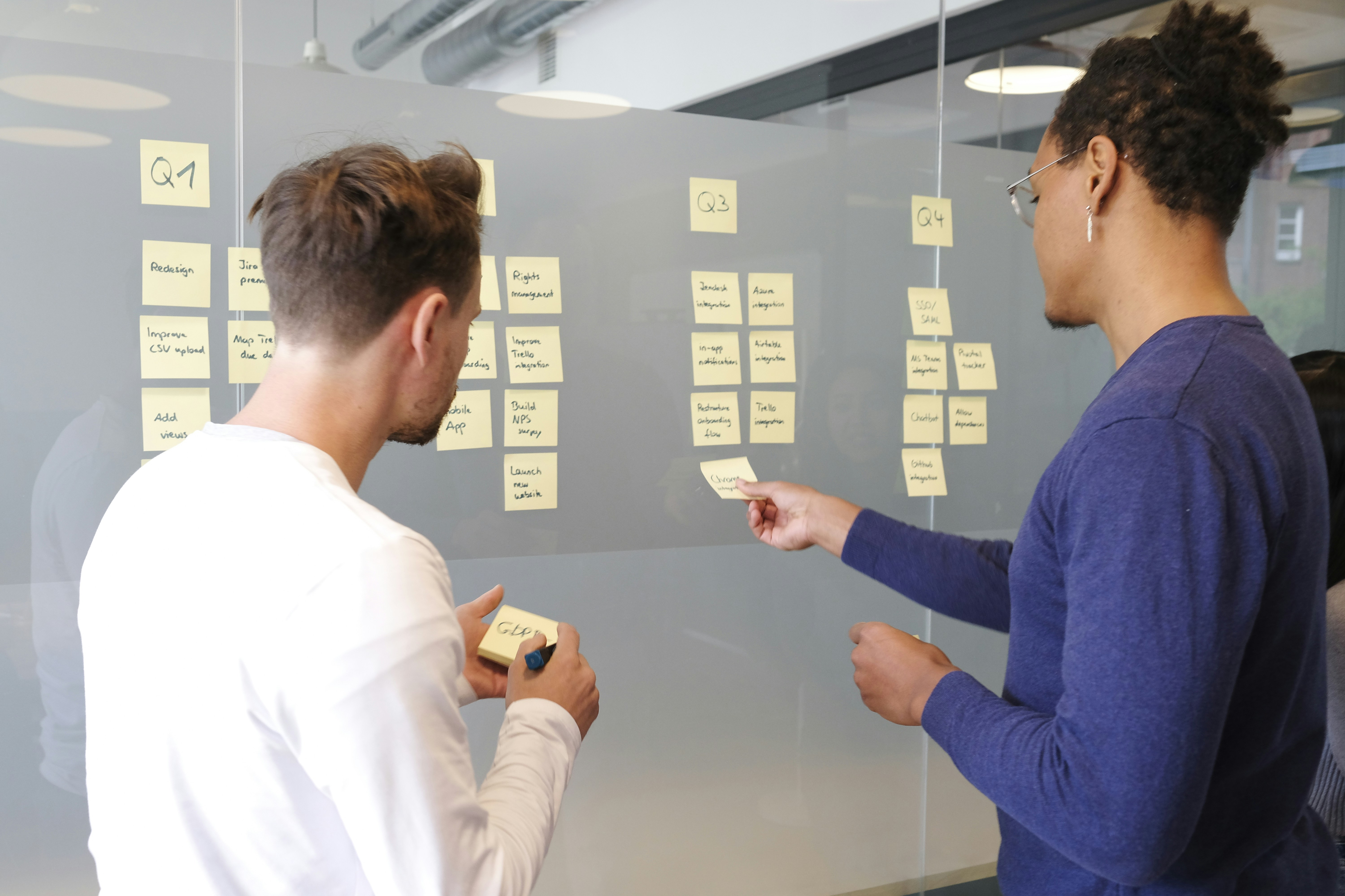 Two People Setting up Sticky Notes on the Board - Workflowy Alternatives