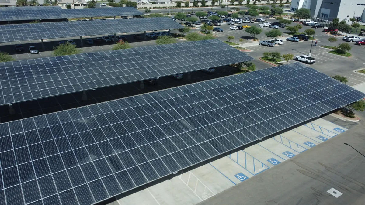 Drone view of a row of solar carports over a commercial parking lot in Bakersfield, CA