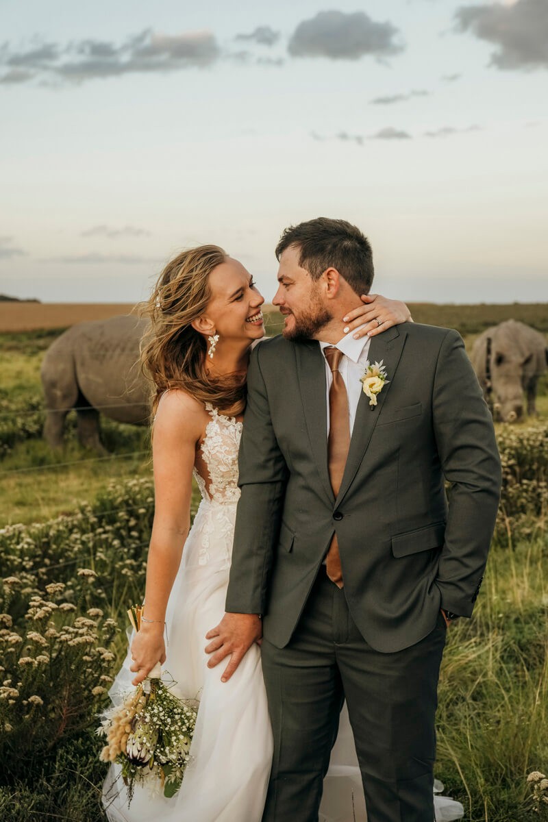 Couple portrait with rhinos in background during Lombardini wedding
