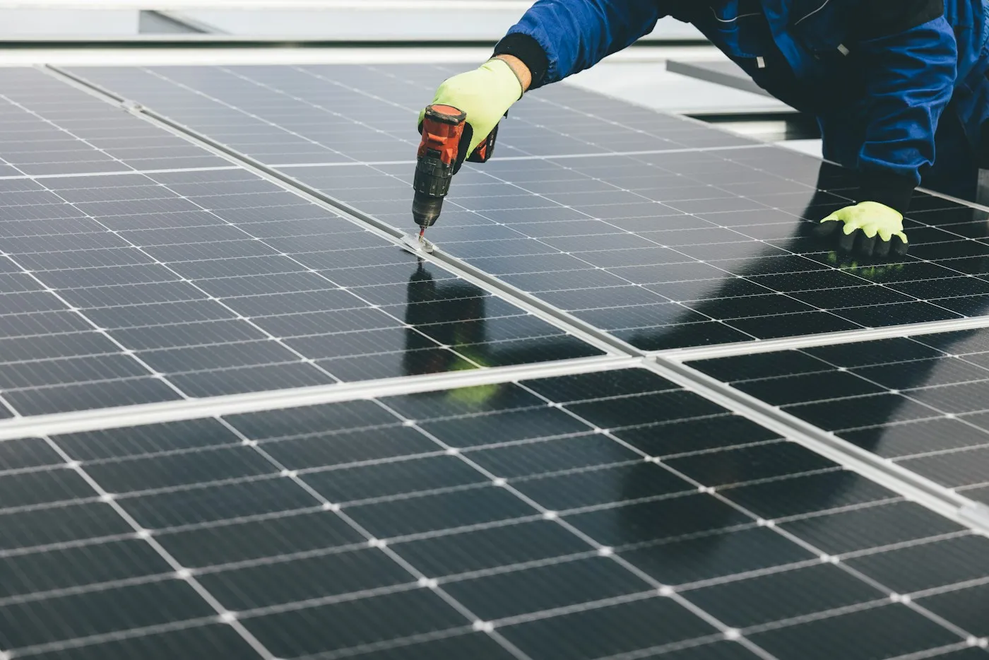 Handwerker mit Werkzeug bei der Montage von Solarmodulen auf einem Dach