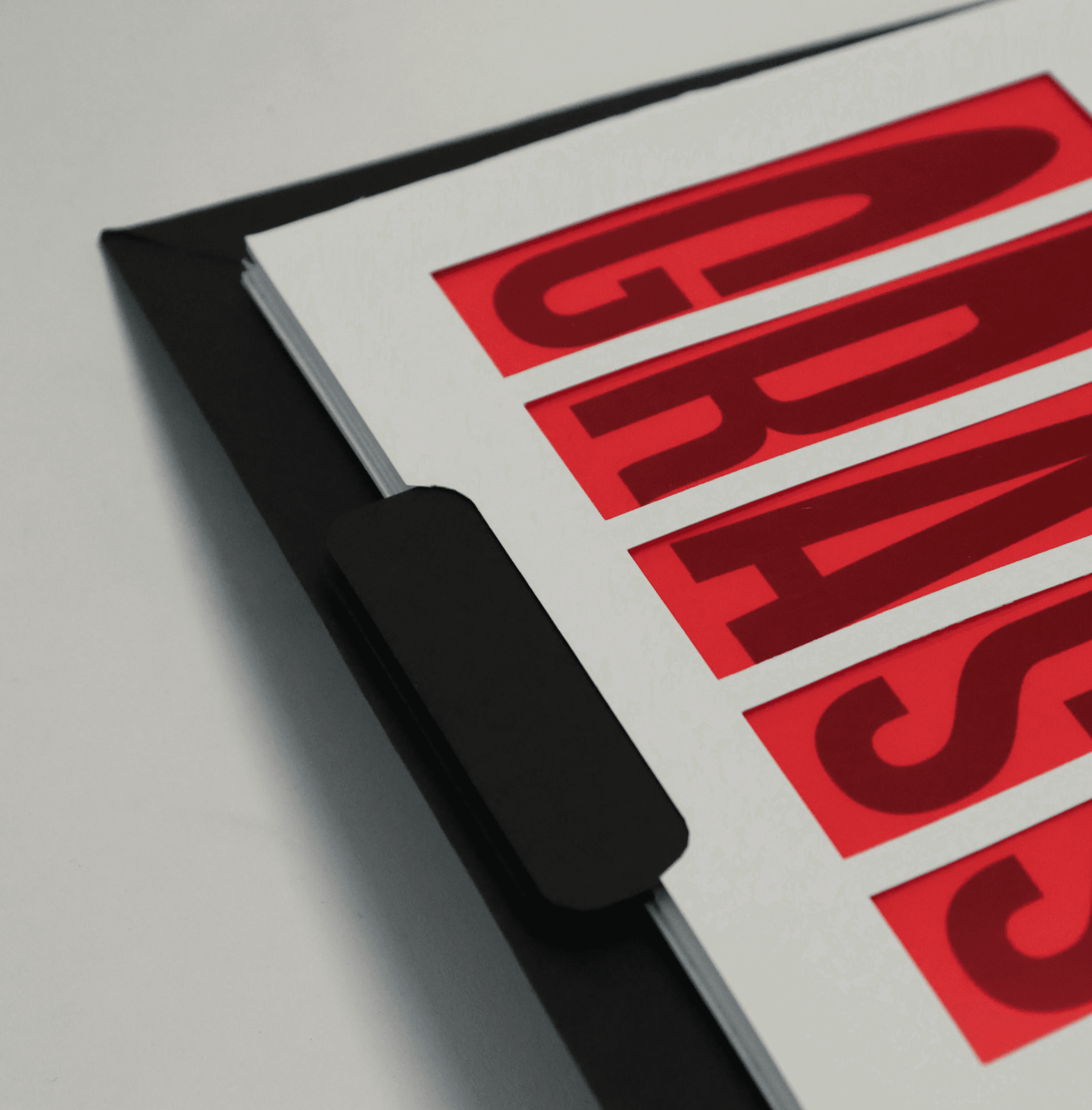 Close-up showing a rounded indent in a book page with a black slider pull-tab behind it