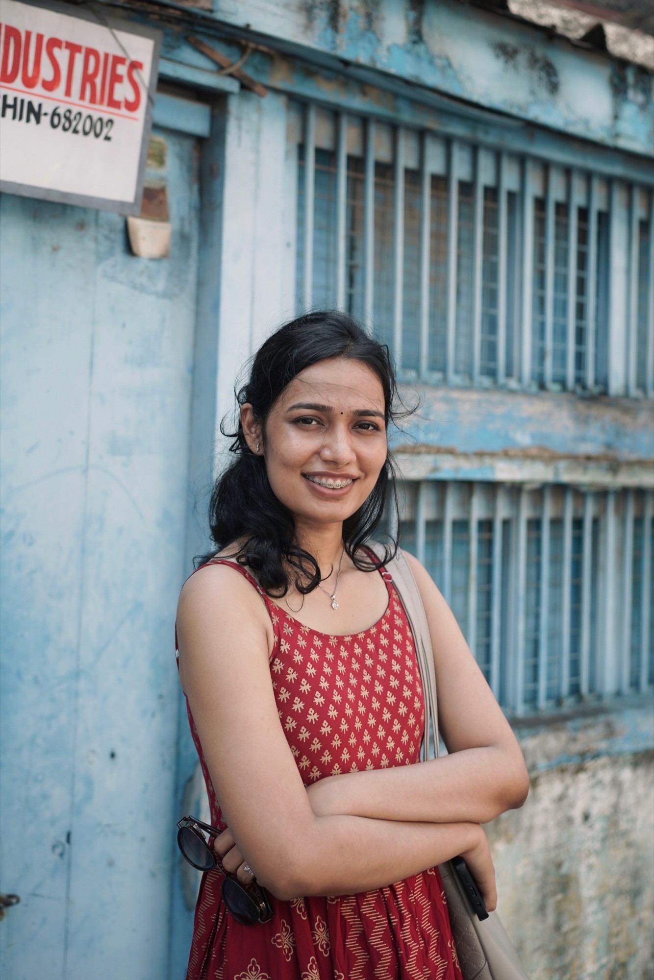 Arms folded, smiling against the blue shutters