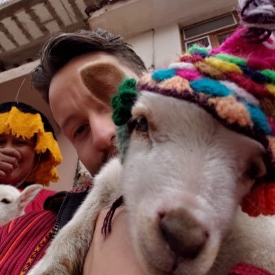 A person writing in a notebook at a table with a glass of water, lit by natural sunlight.