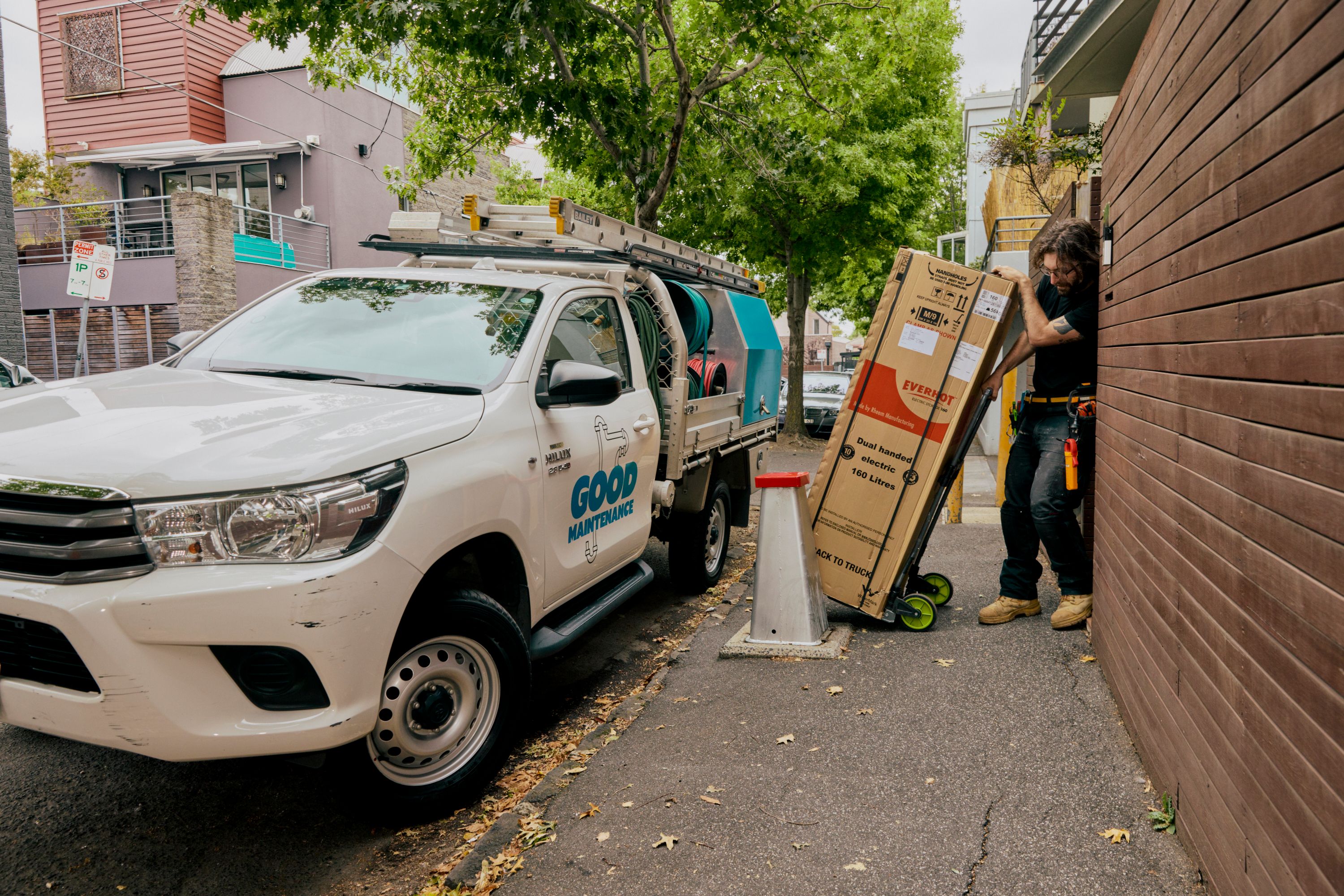 Good Maintenance tecnician wheeling a new hot water system on a trolly.