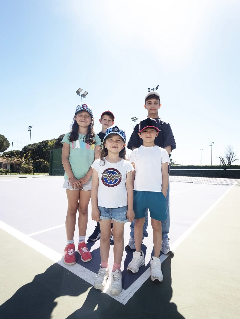 Groupe d’enfants portant des casquettes The Prompt Factory sur un court de tennis