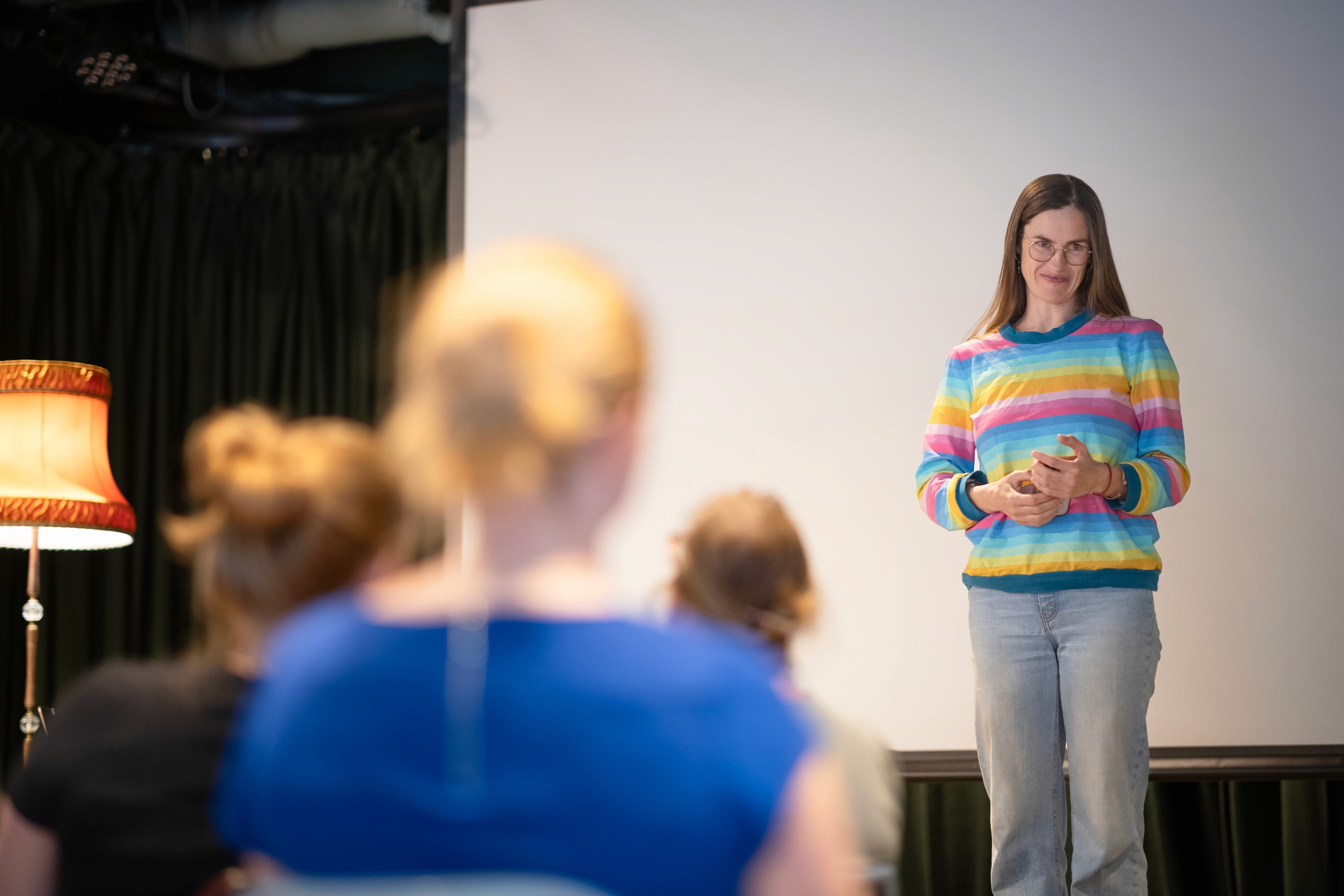 A women addressing people sitting down in a room