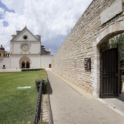 石头小道通向一座带圆形窗户的白色教堂，左侧是绿色草坪，右侧是拱形门入口。