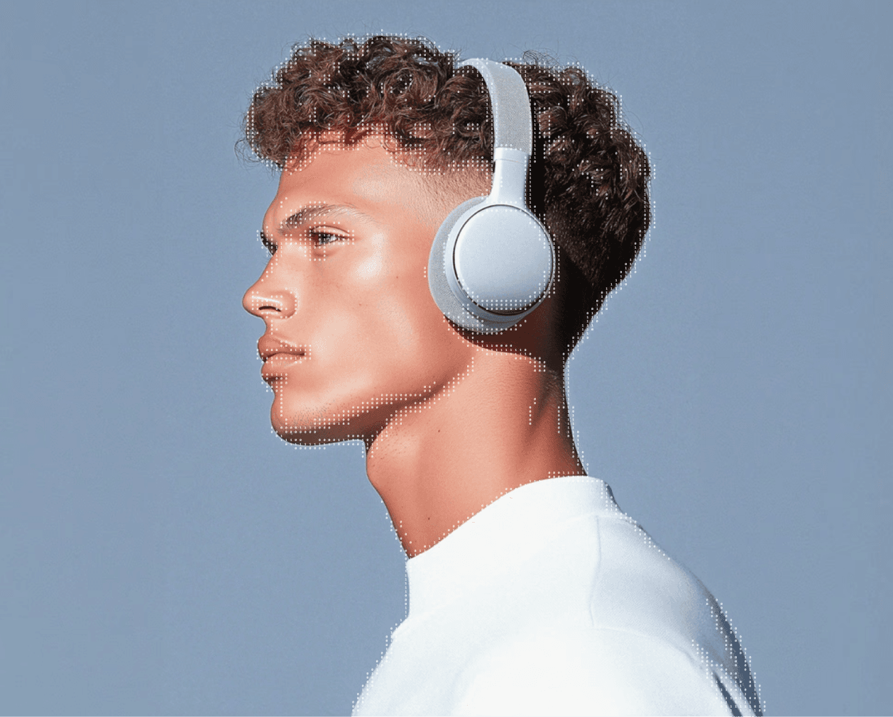 A man wearing headphones smiles against a solid blue background.