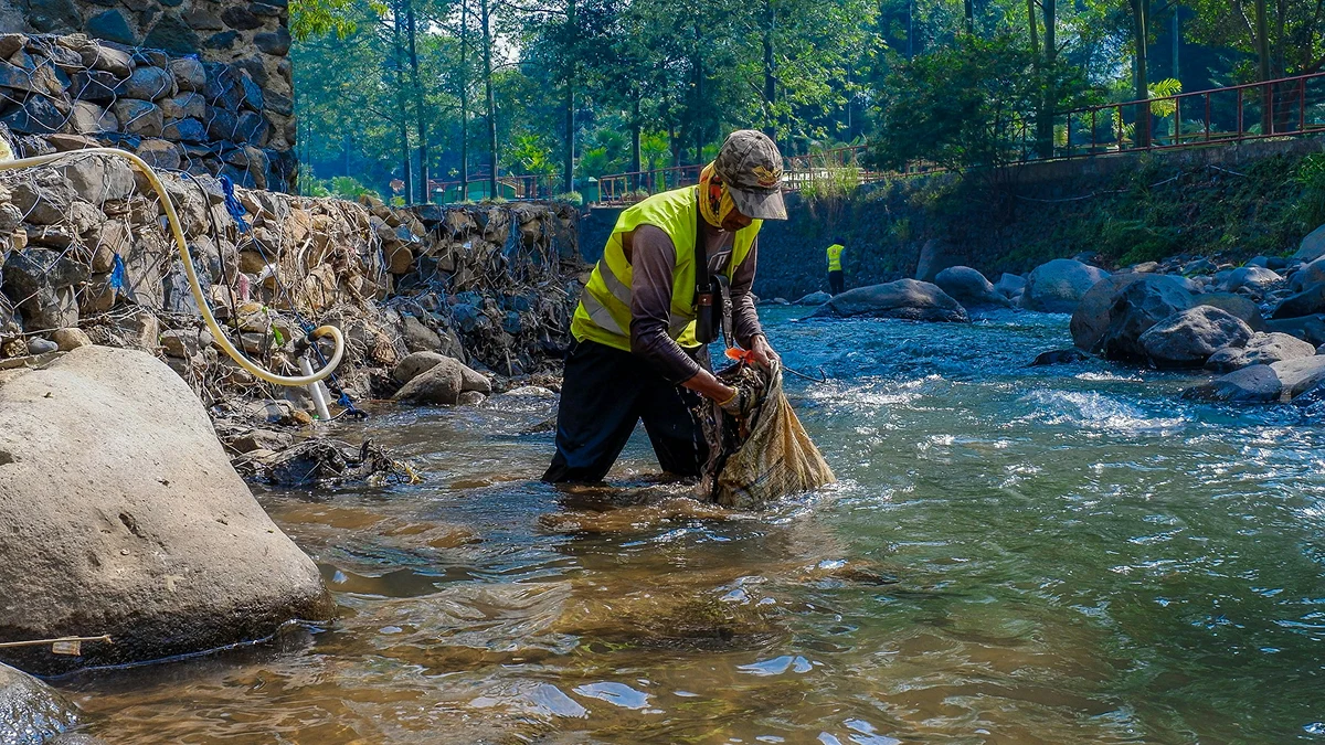 Worker cleaning a natural stream as part of an outdoor environmental care activity.