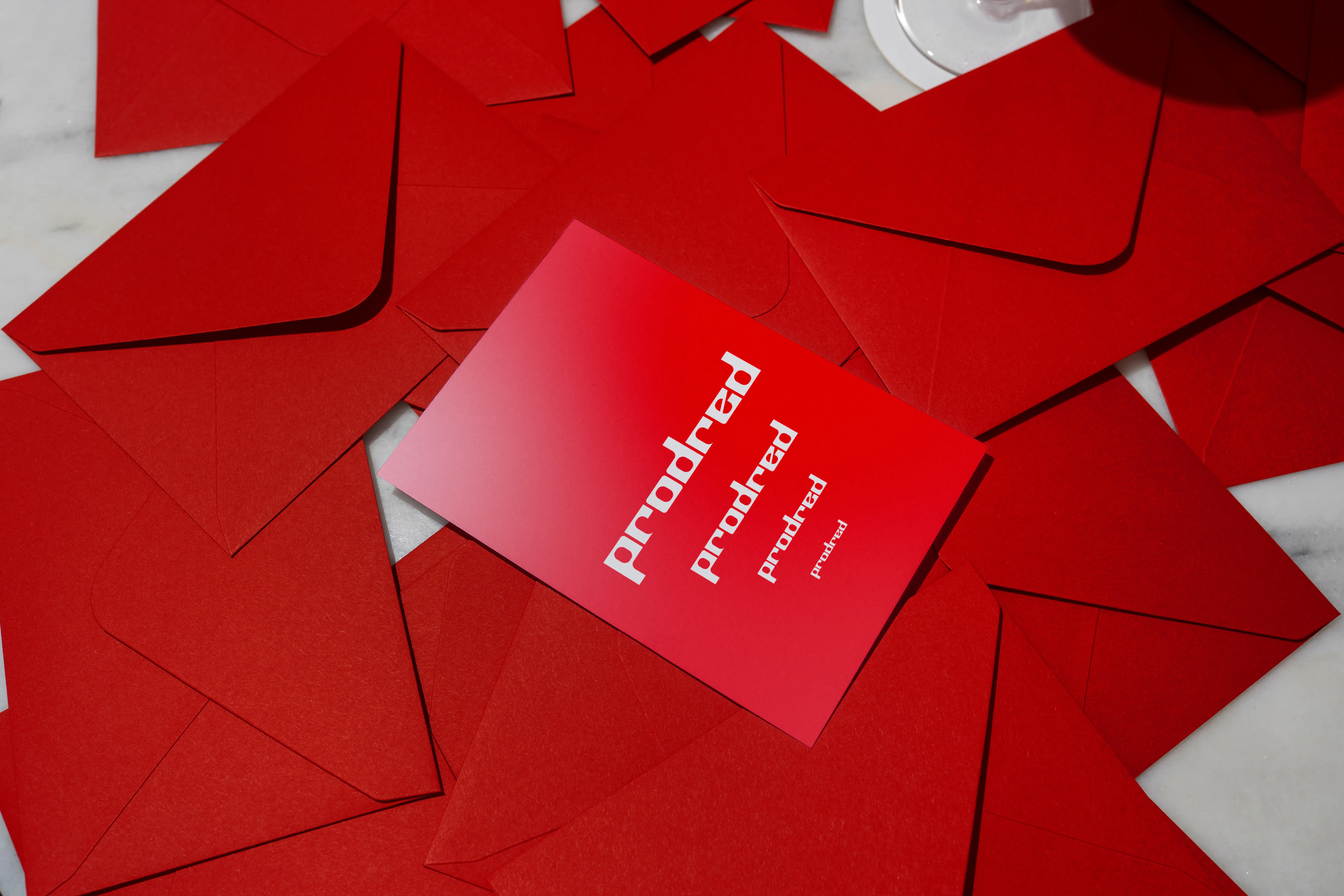 Professional brand card with repeated Prodred typography placed amidst a large collection of vibrant red envelopes.