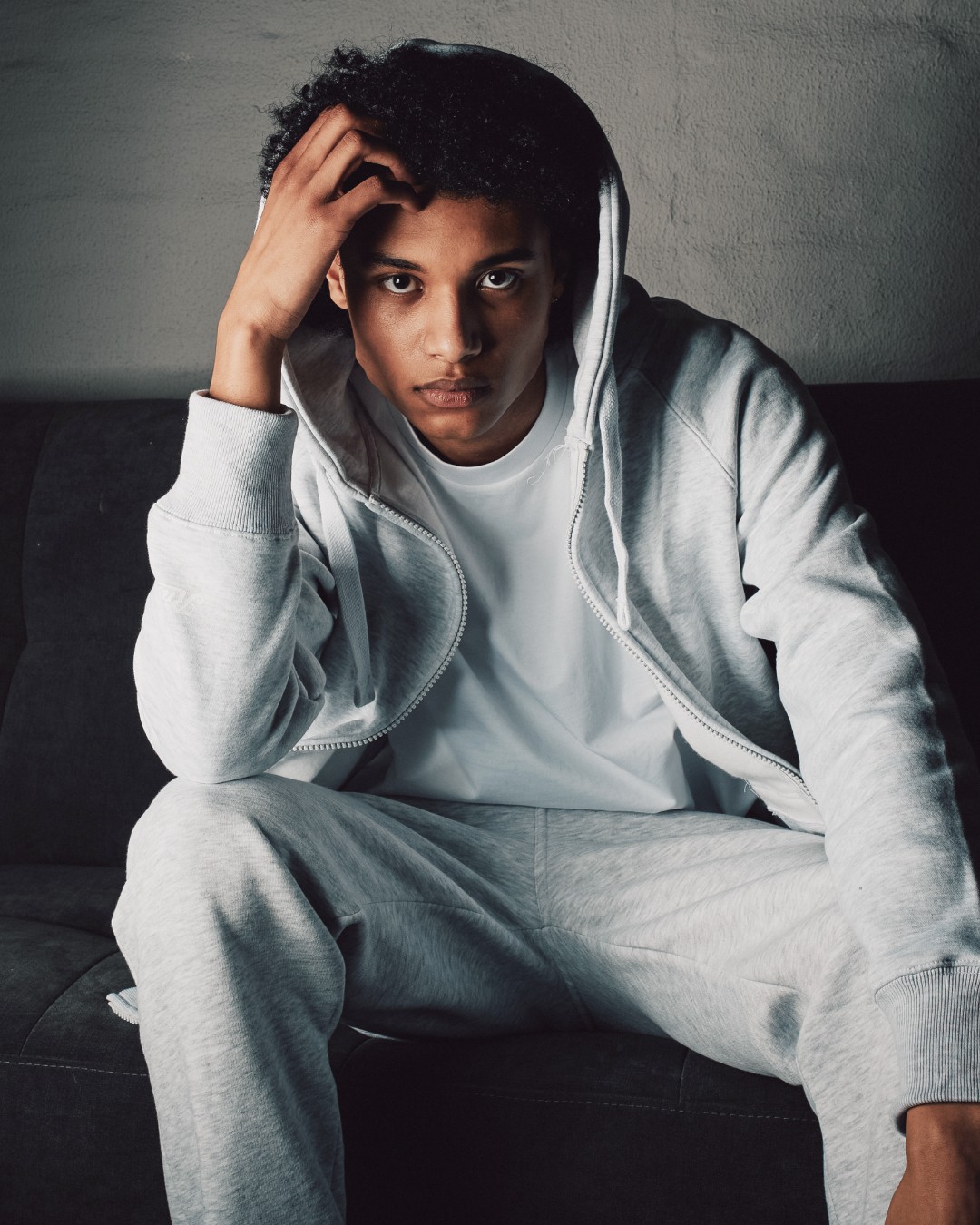 Person dressed in grey slacks sitting on a couch in a dark room