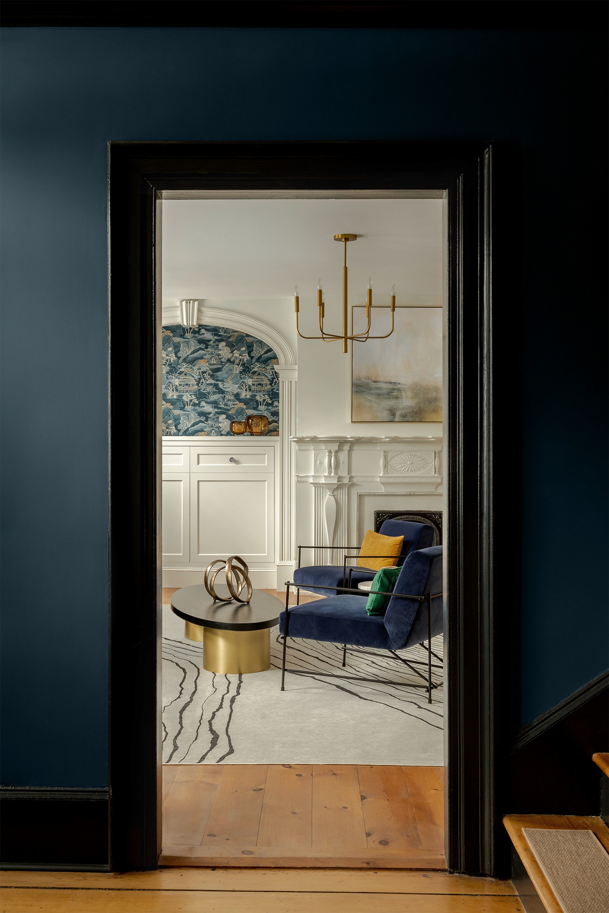 Hattan House living room viewed through navy hallway, chesterfield sofa and antique chandelier beyond doorway