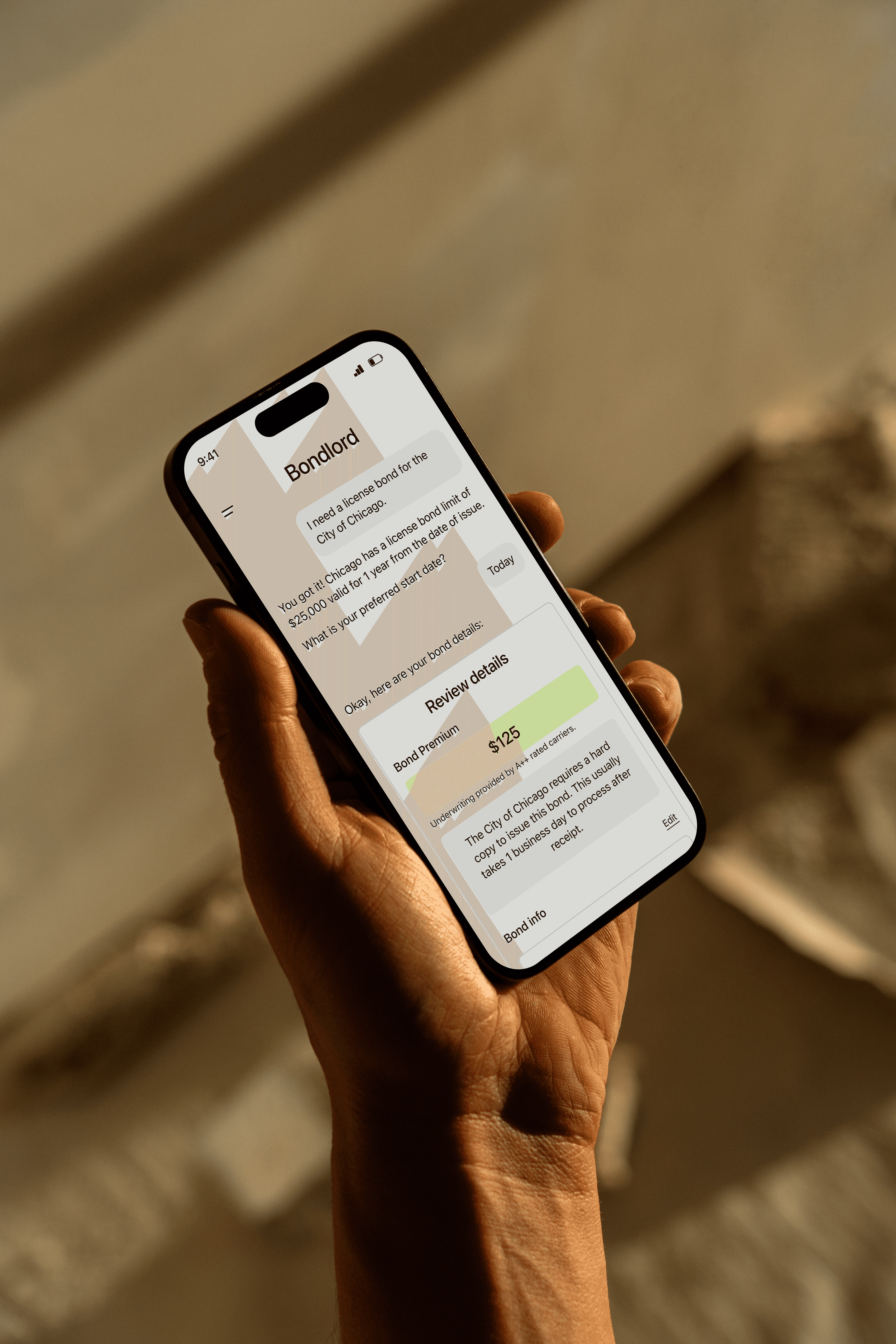 Hand holding a smartphone displaying the Bondlord app, where an AI chat helps a contractor request and review a license bond for the City of Chicago, including bond details and premium.
