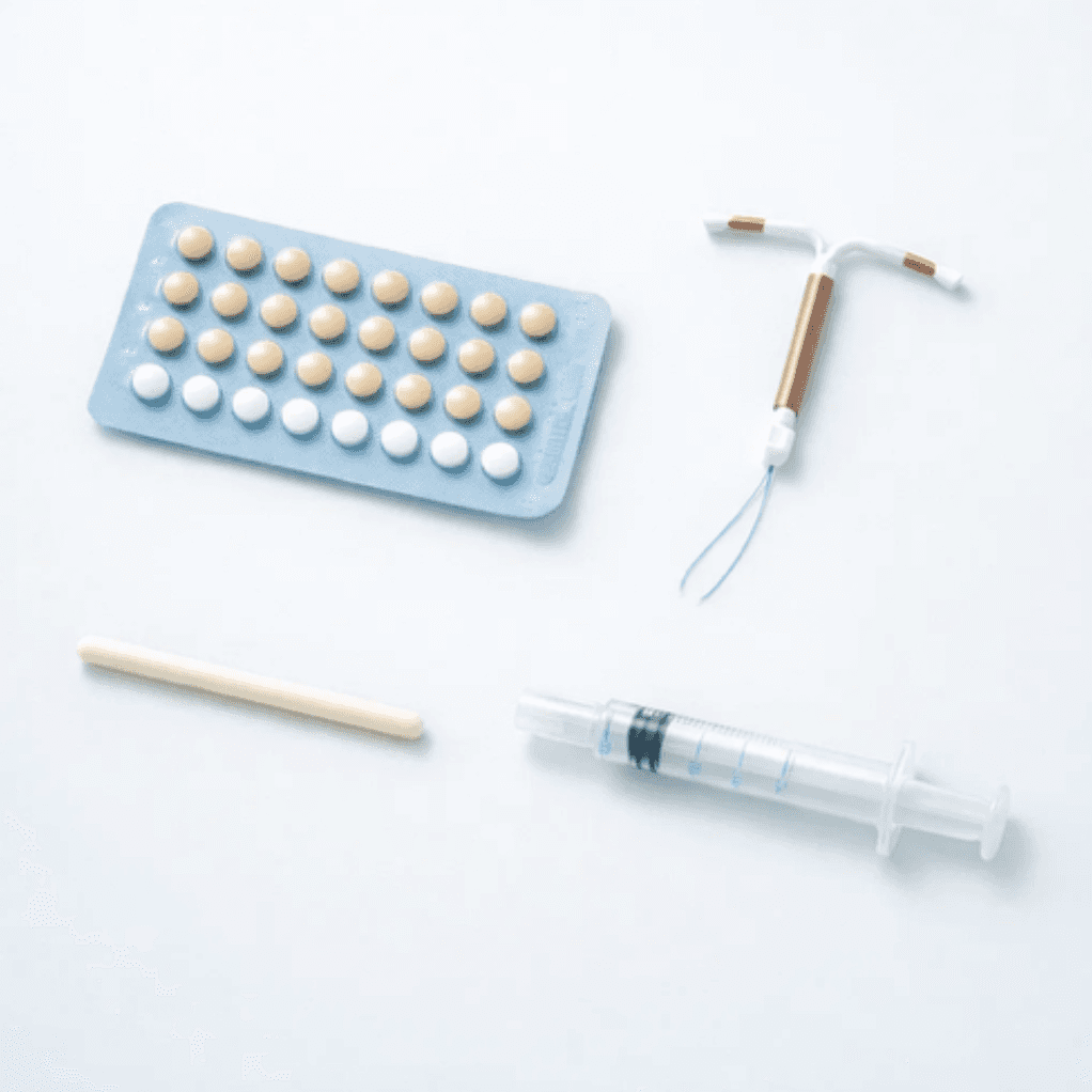 อุปกรณ์คุมกำเนิดหลายรูปแบบ ได้แก่ ยาเม็ดคุมกำเนิด ห่วงอนามัย (IUD) ยาฝังคุมกำเนิด และยาฉีดคุมกำเนิด วางบนพื้นหลังสีขาว