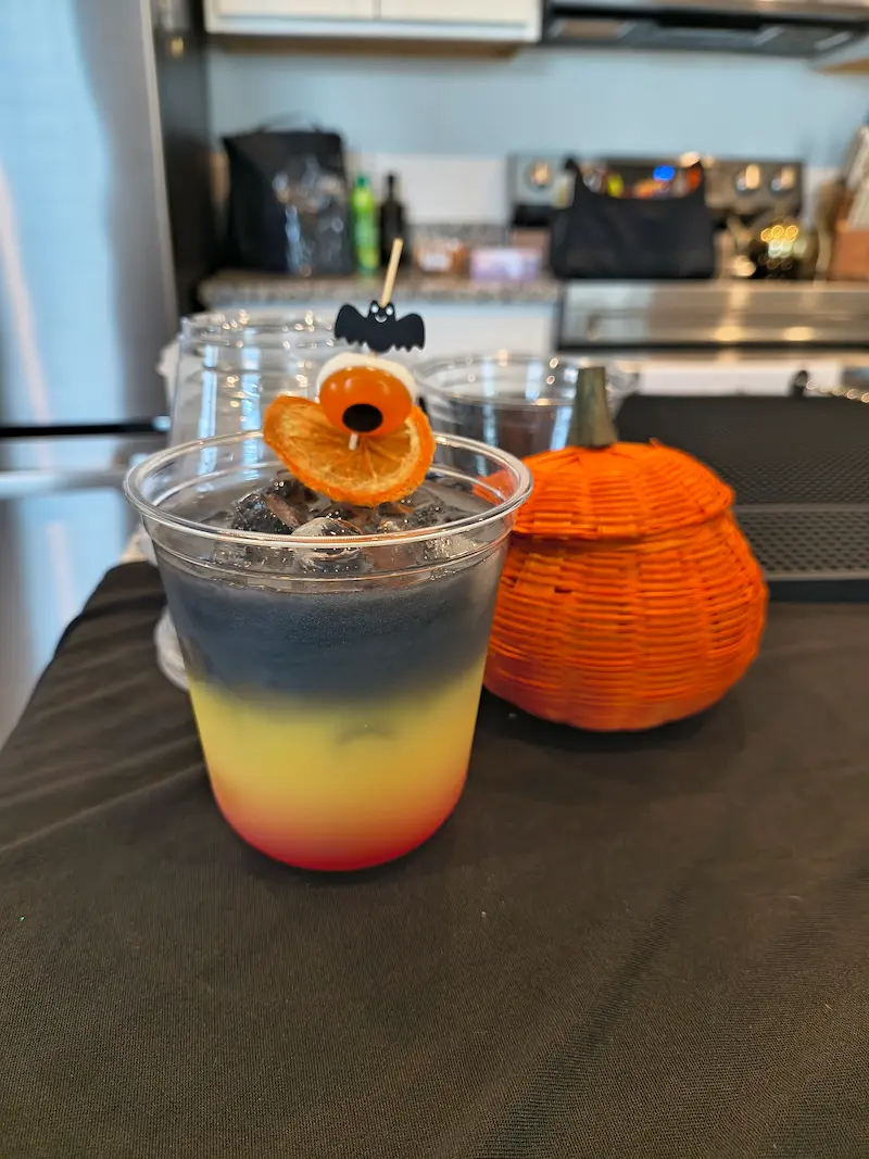 A refreshing cocktail in a martini glass features slices of cucumber and mint leaves, set on a dark wooden table with a striped cloth and a knife nearby, evoking a relaxed Bradenton, FL vibe.