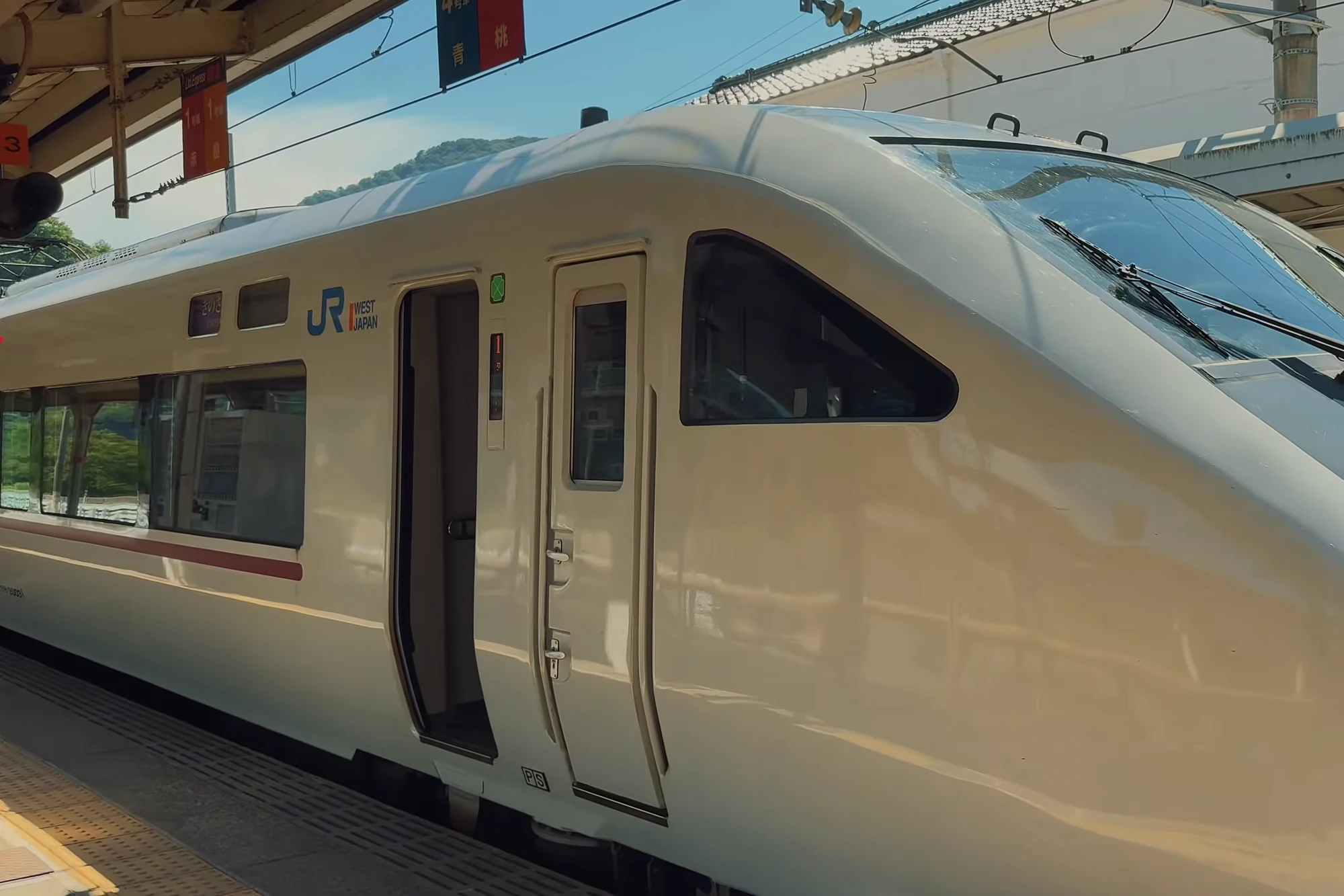 A white JR West limited express train standing at Kinosaki Onsen station platform.