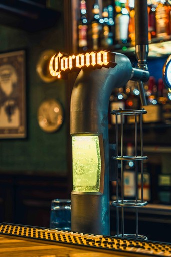 A vibrant bar scene with glowing green lights, featuring a bottle and a cocktail glass on the counter.