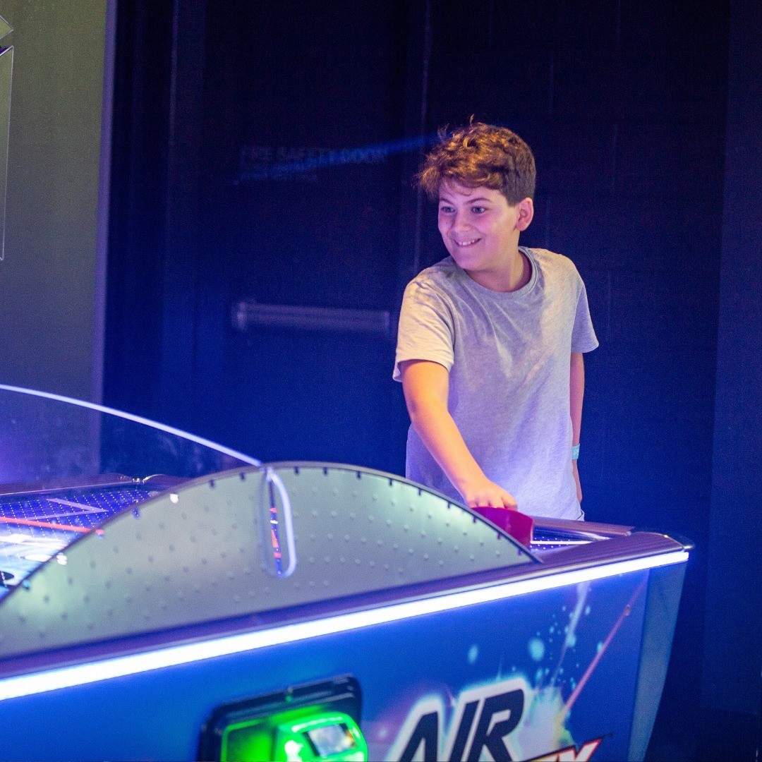 A kid wearing headphones while sitting in front of a computer at Fortress