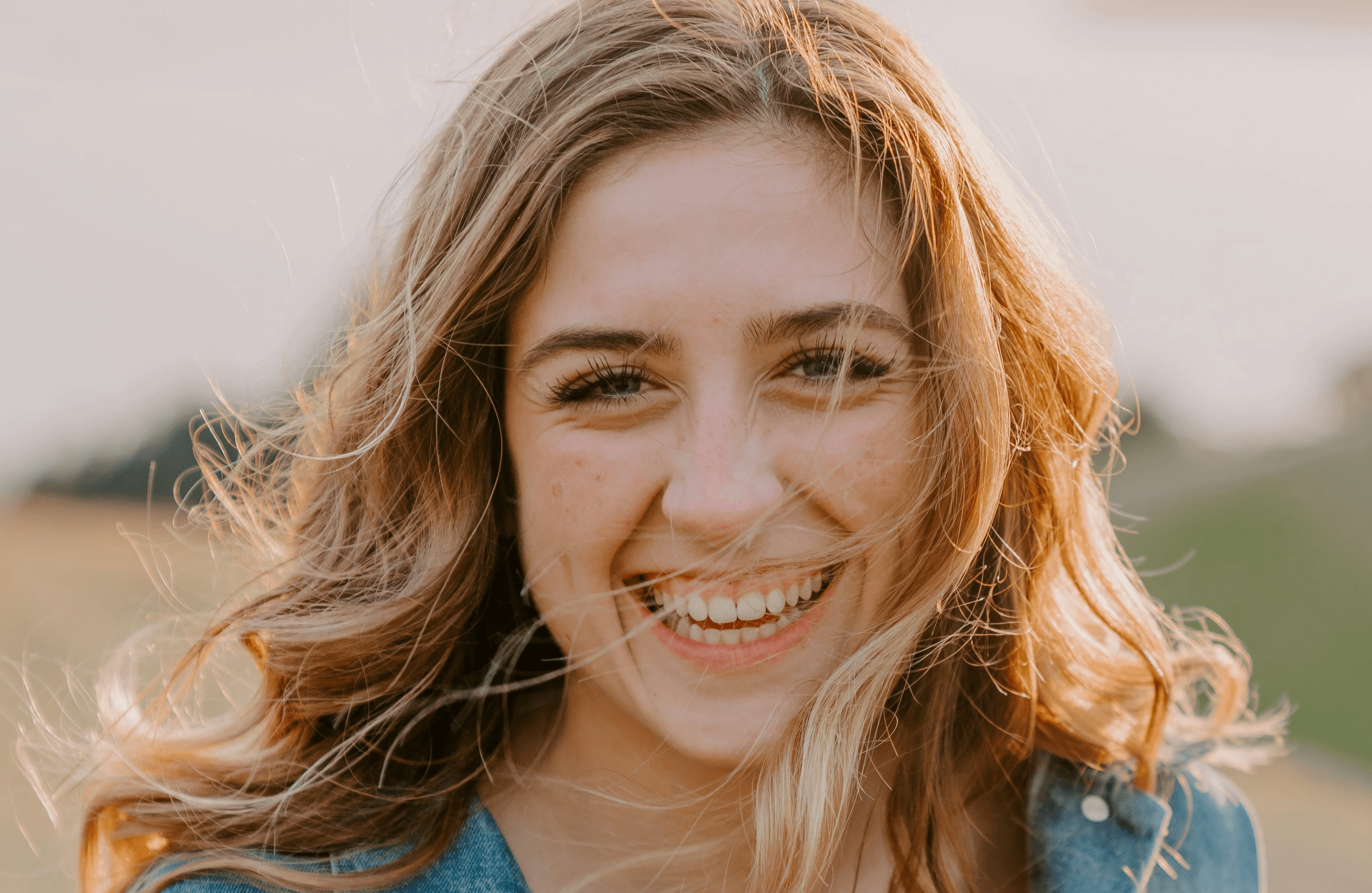 smiling woman sitting on grass during daytime