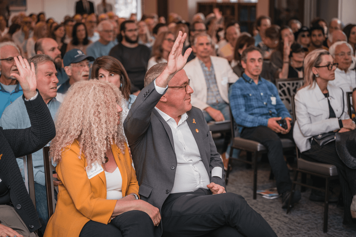 Audience members raising their hands during an indoor event