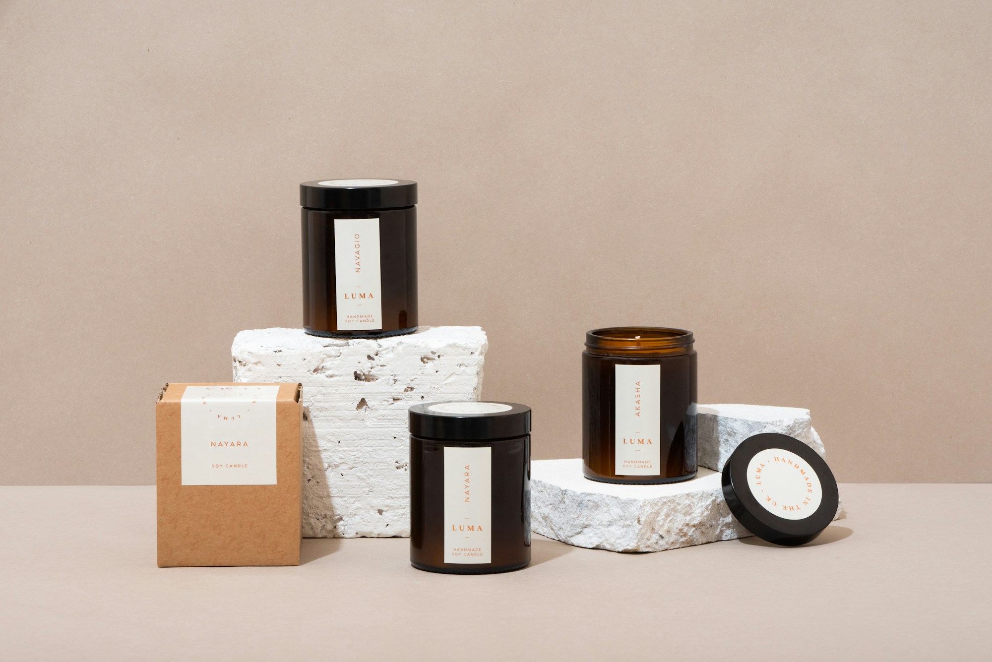 Amber glass candle jars on white stone blocks against a beige wall