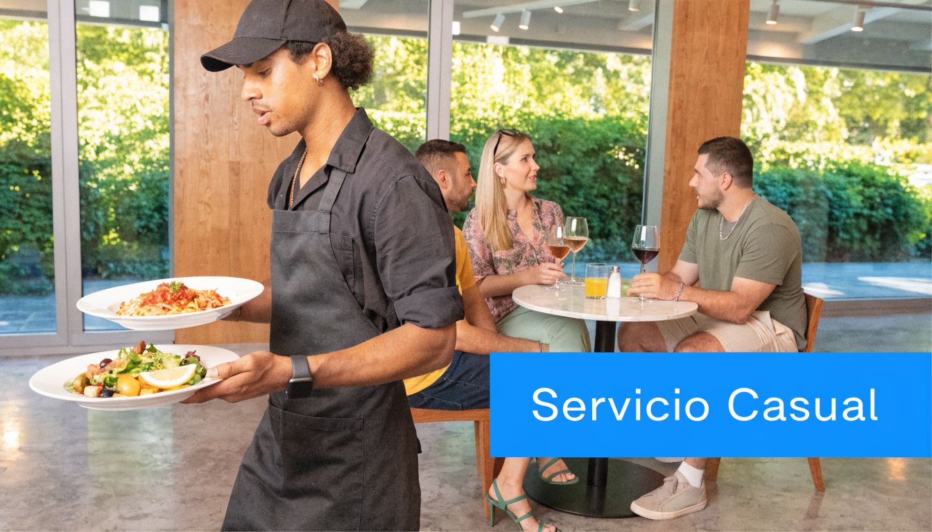 Un camarero sirve platos de comida en un restaurante casual con clientes disfrutando en sus mesas.