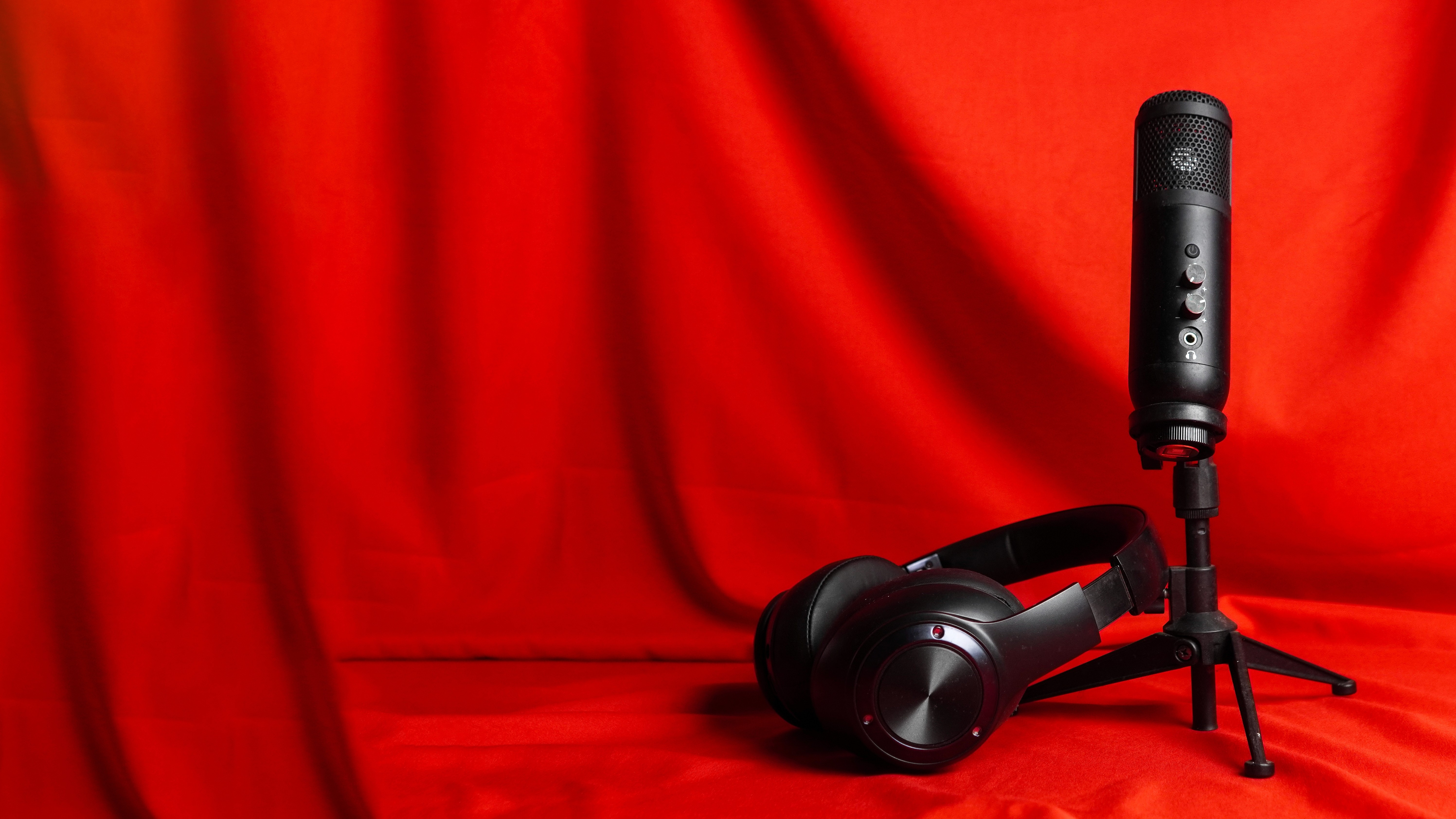 Wireless headphones and condenser mic on red curtain background 