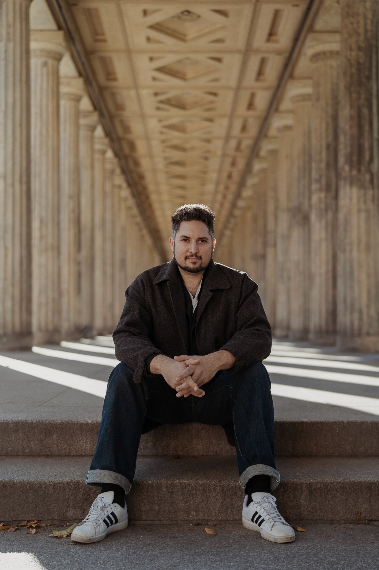 Founder of StoryOS sitting under classical columns in Berlin, symbolizing structure and narrative clarity