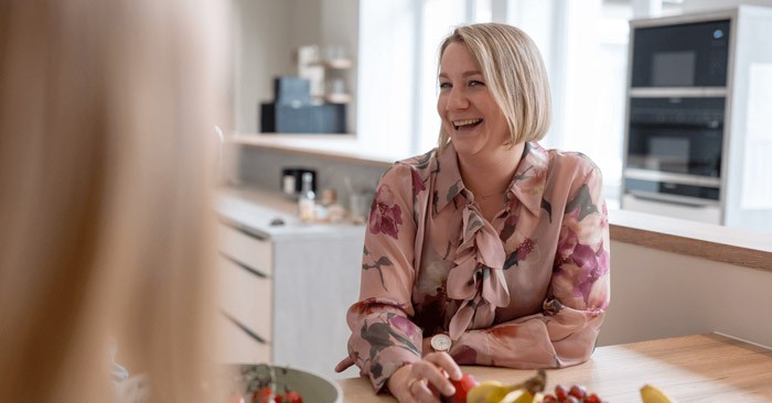 Eine Geschäftsführerin in blumiger Bluse sitzt im Gespräch an einem Tisch im Büro von SLB.