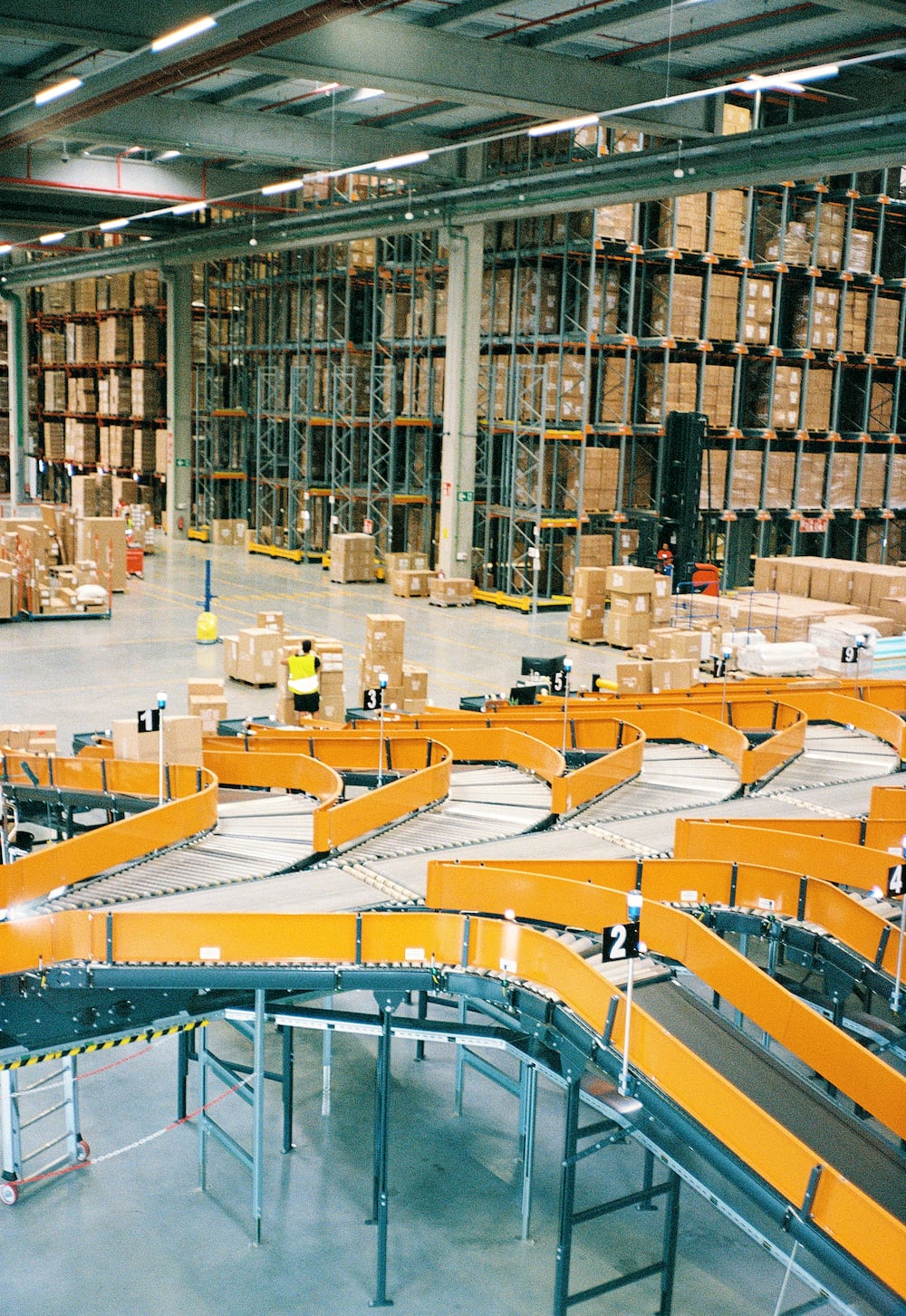 Close-up view of an orange shipping container suspended mid-air against a cloudy sky.