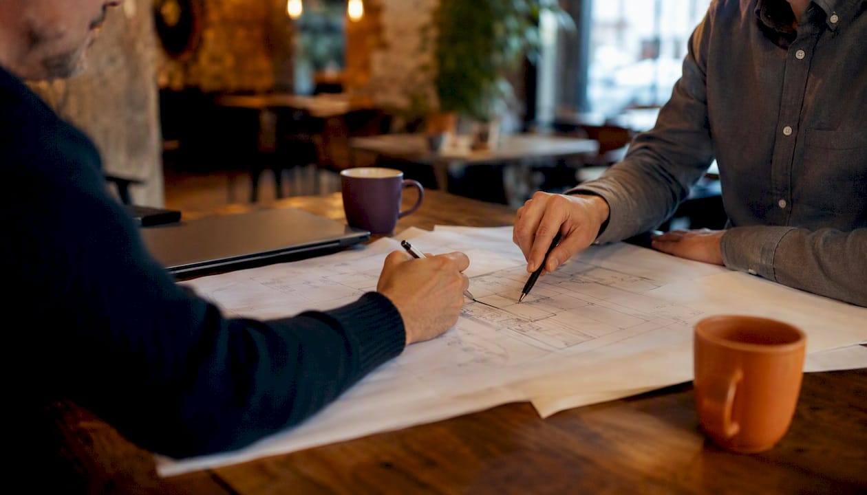 Hands collaborating on AI project blueprint