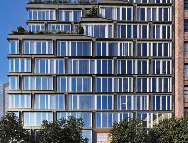 Tall modern skyscraper with vertical lines, viewed against a clear blue sky.