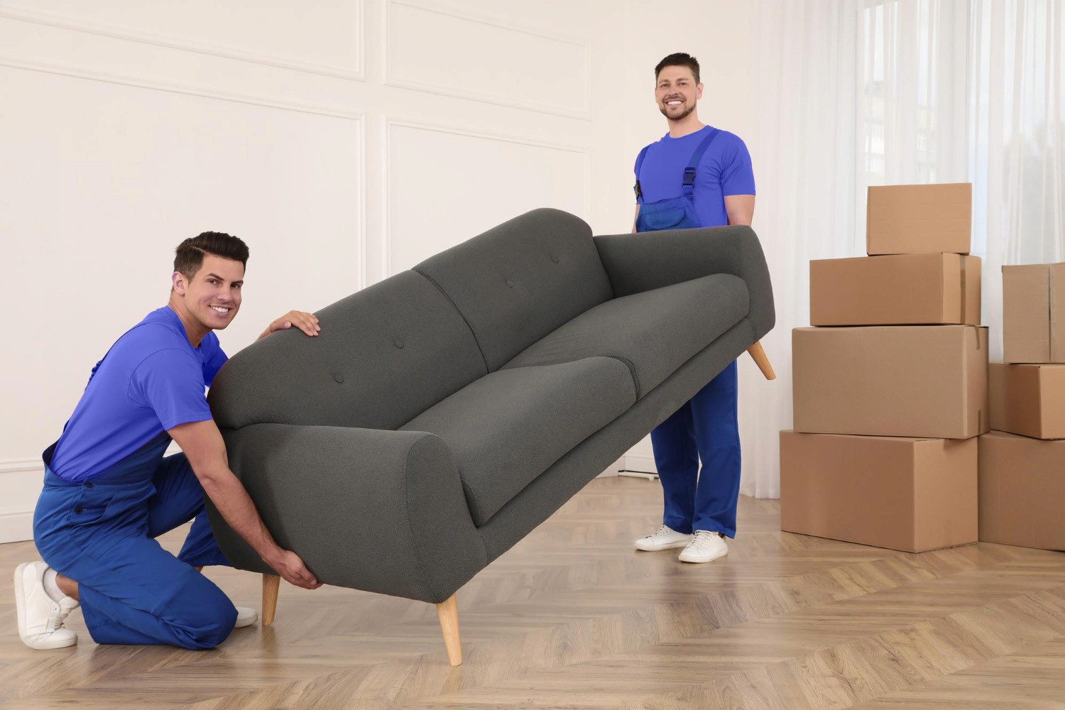 Two uniformed men removing a sofa from a room.