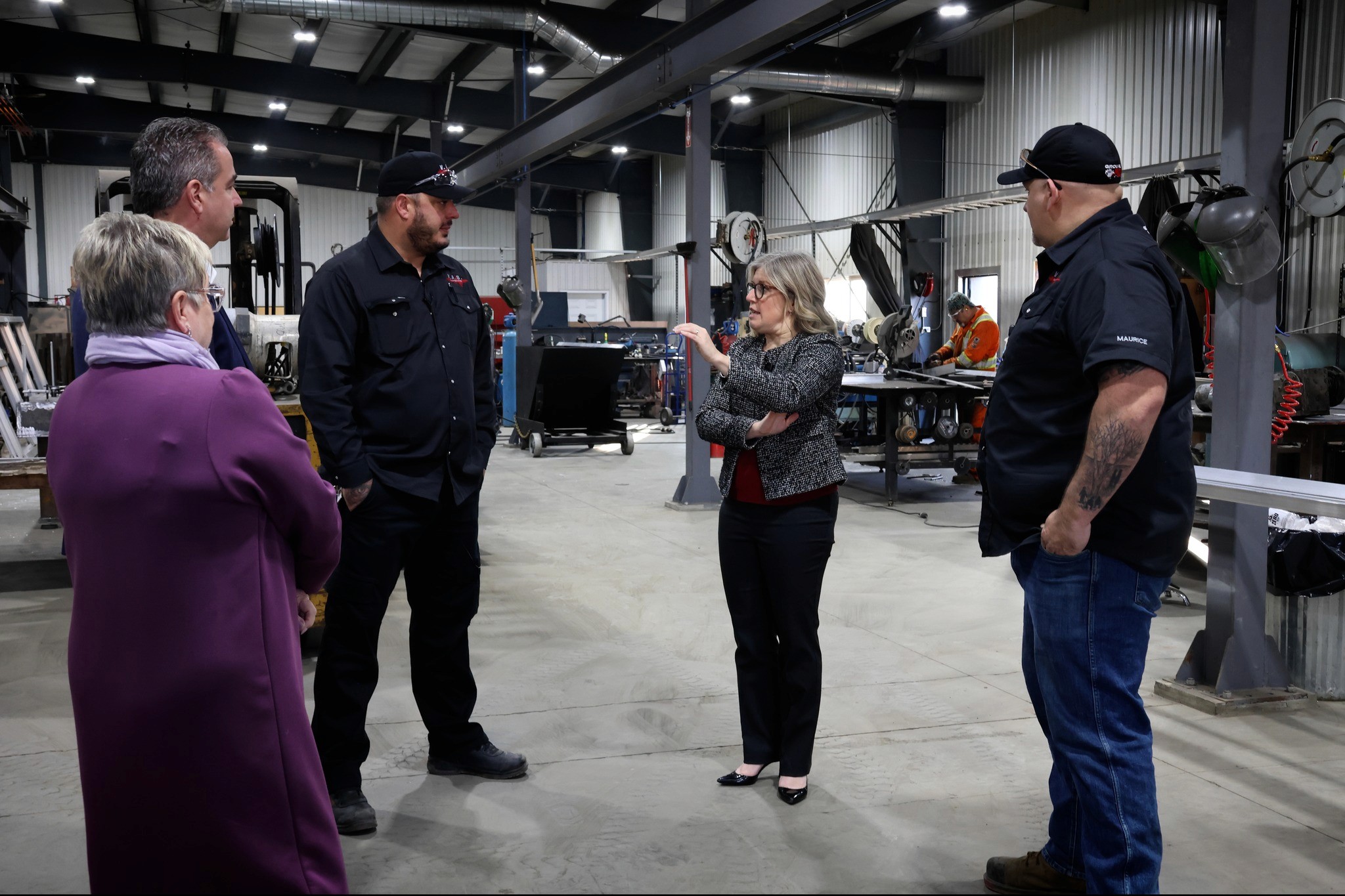 Spacious modern office with large windows, indoor plants, and people working at shared desks.