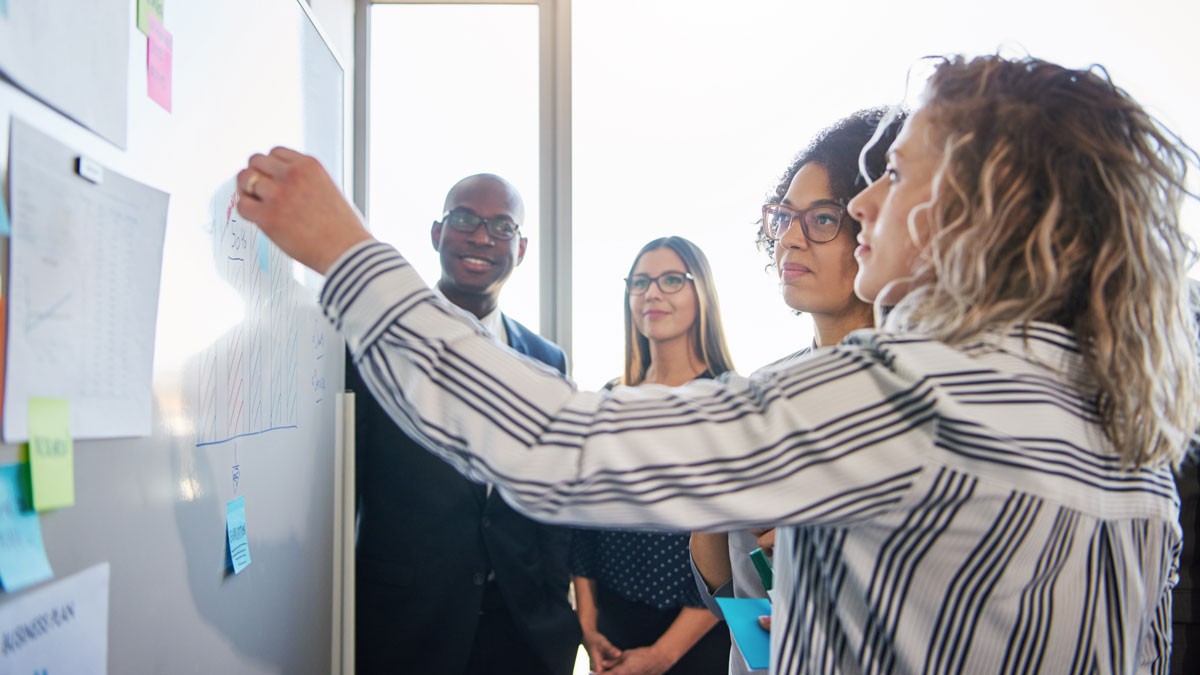 Coworkers strategizing a front of a whiteboard