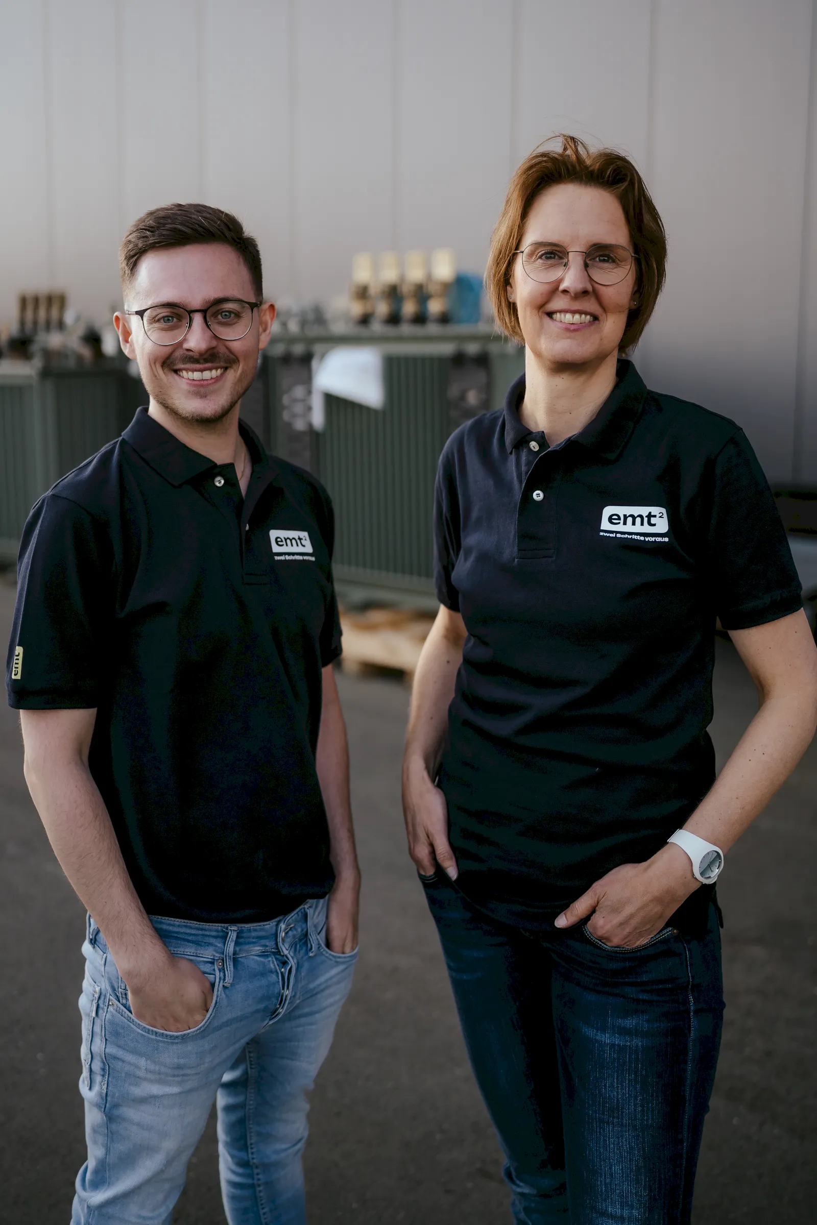 Drei Männer im Gespräch, zwei tragen Poloshirts mit "zwei Schritte voraus"-Aufdruck.