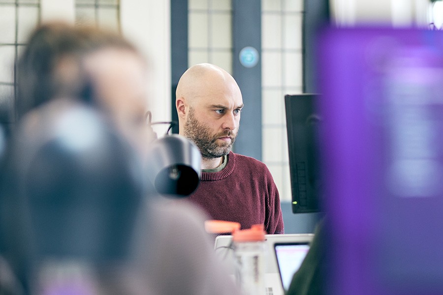 A man sat infront of multiple monitors