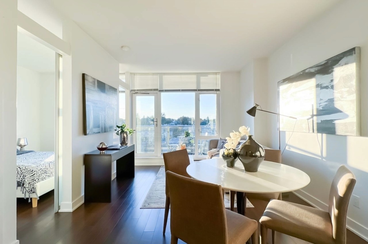 Bright, modern dining area with a round table and chairs, featuring large windows that open to a scenic view.