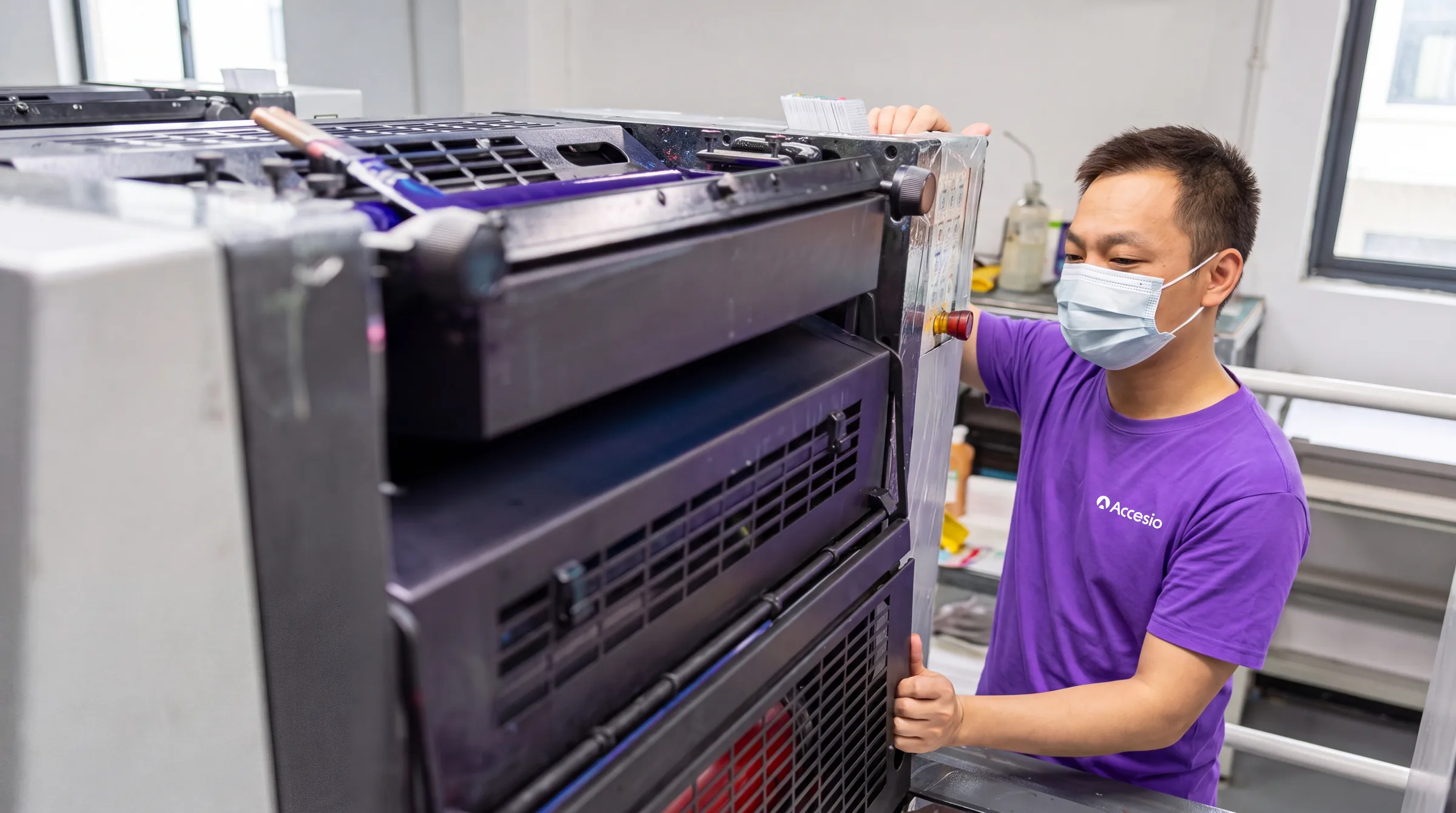 Accesio operator checking printed sheets on the press during a production run