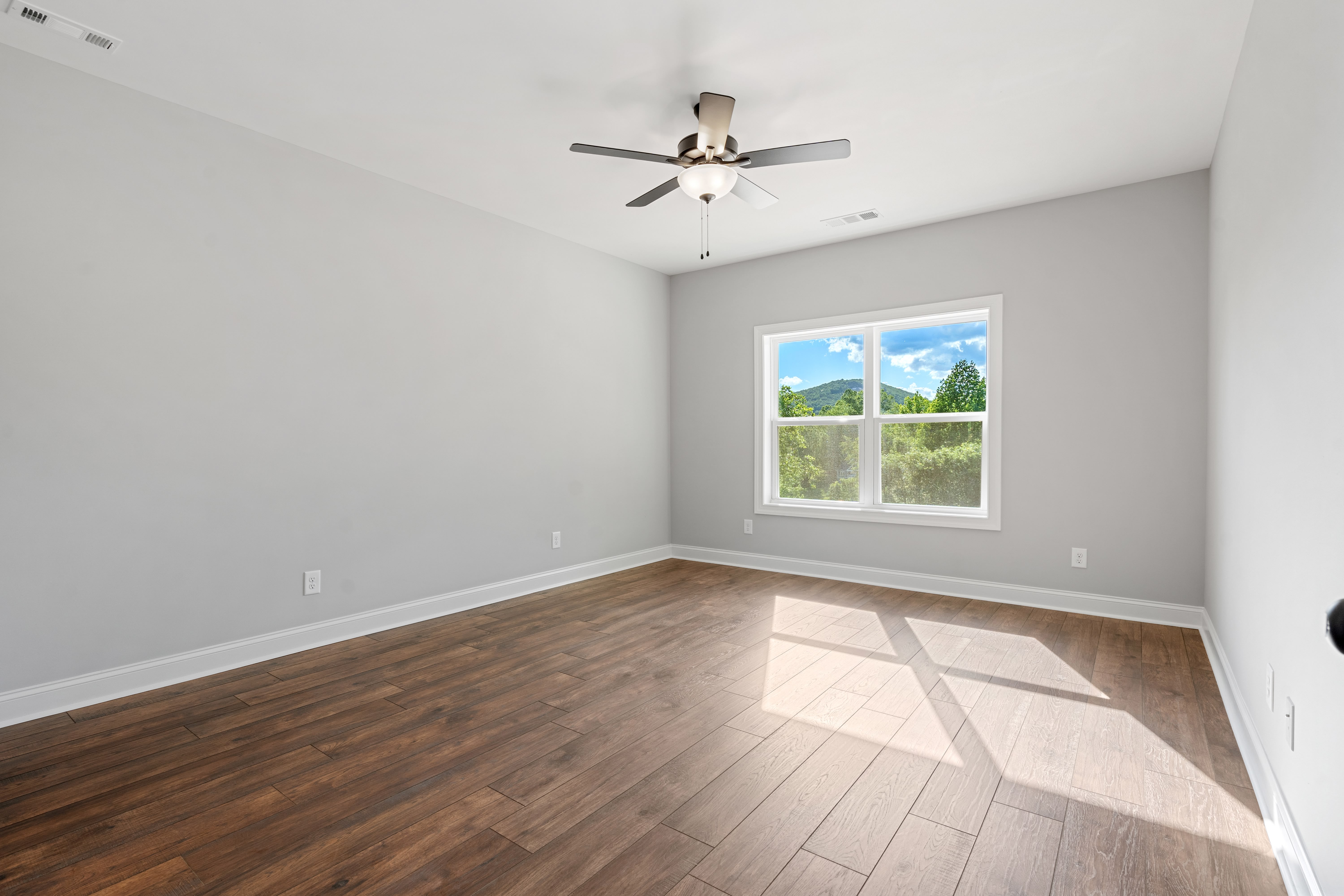 Spacious master bedroom with sliding farm door and hardwood floors