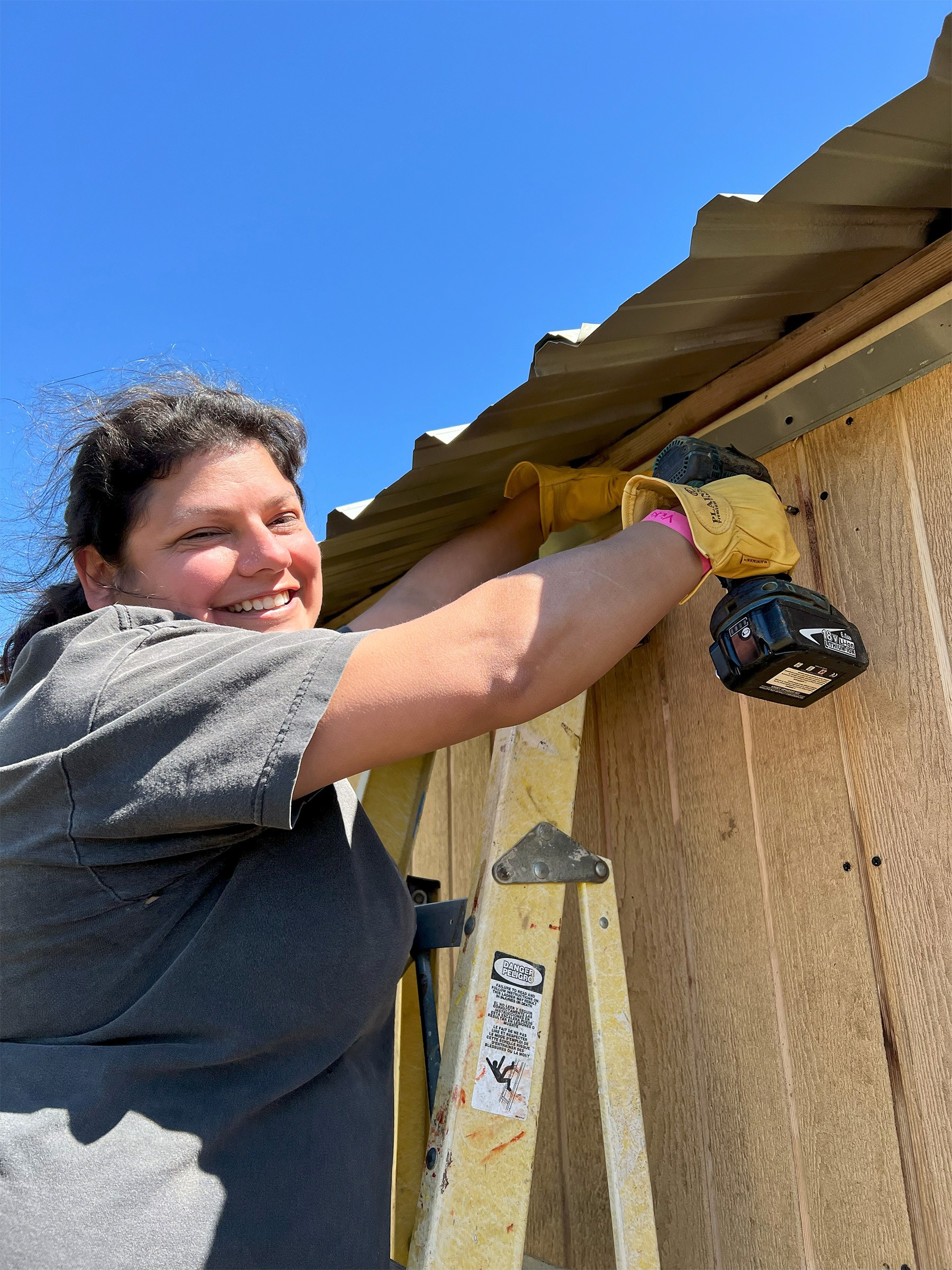 gemini legal employee volunteering building homes girl smiling with drill on ladder