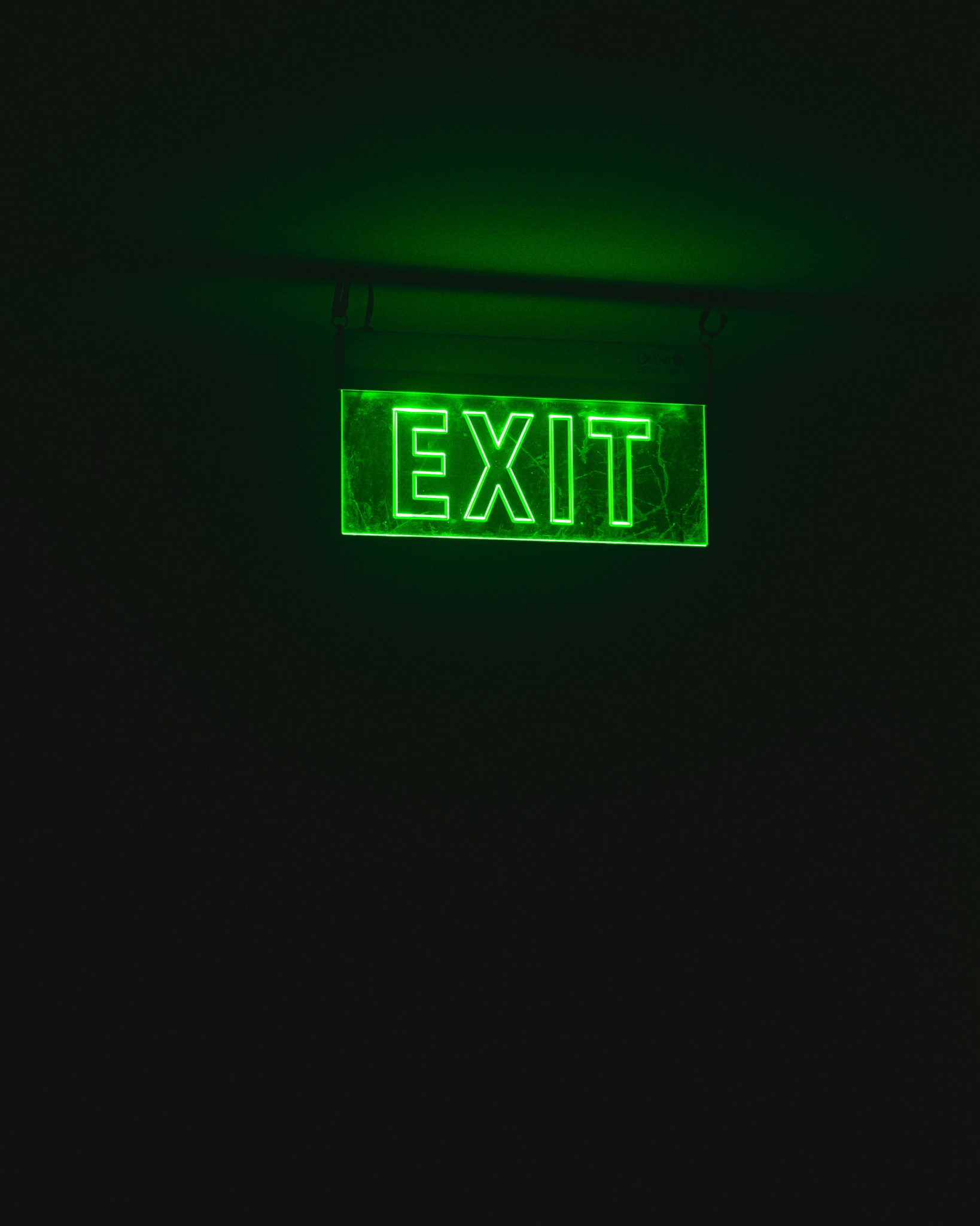 A green illuminated emergency exit sign in a building.